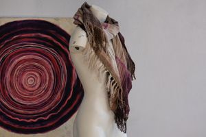 Handwoven scarf naturally dyed shades of pink, brown and green on a white mannequin in a white gallery space