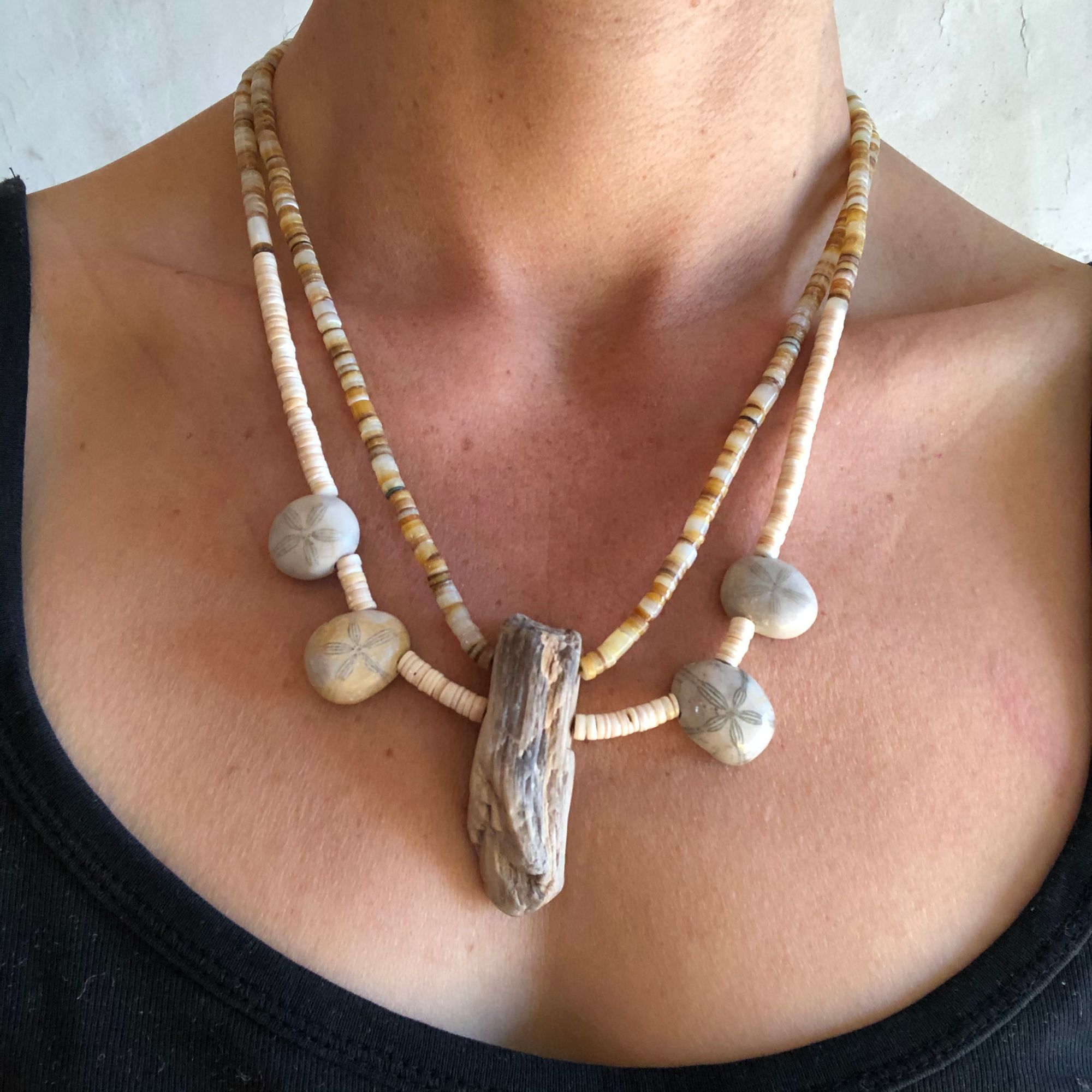 woman wearing a necklace made of shell heishi, fossils and petrified wood