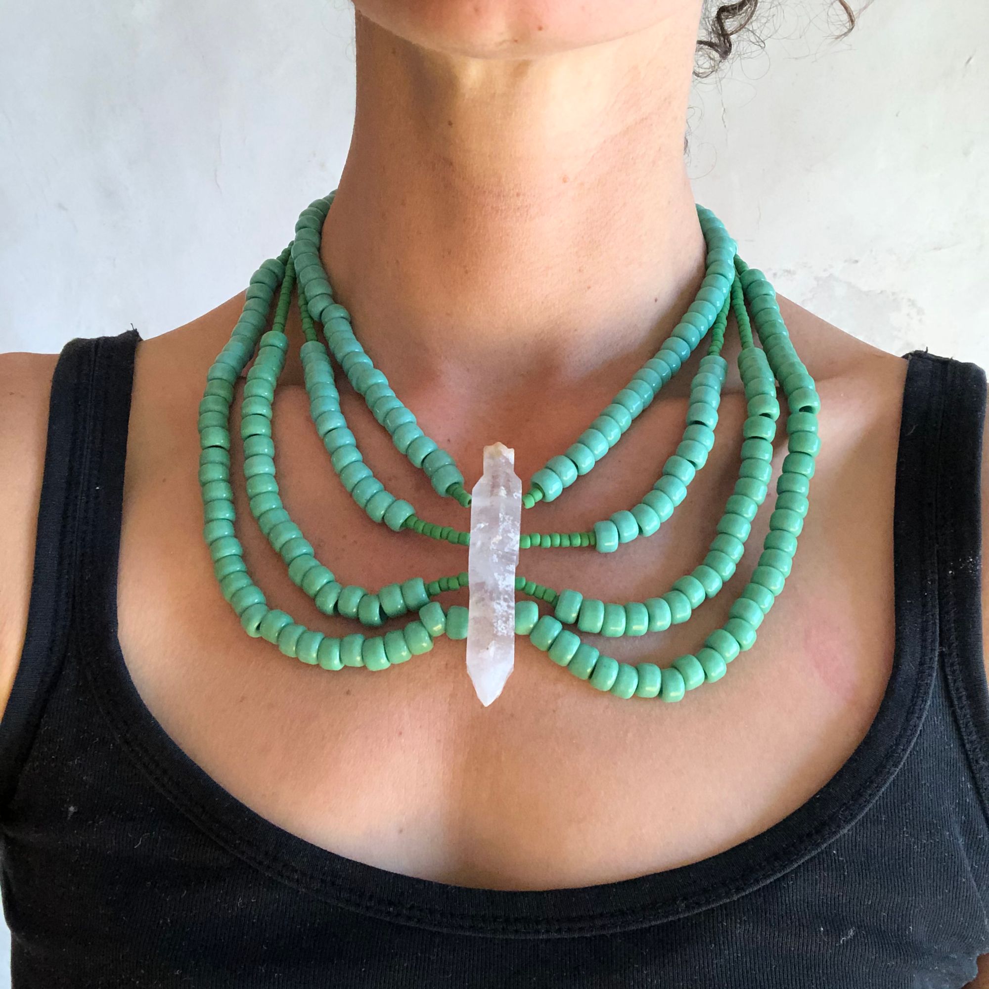 Woman wearing Green beaded necklace with a large double terminated quartz stone at the center