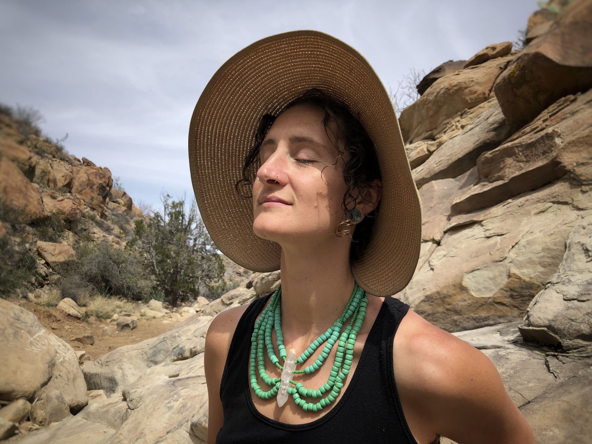woman in the desert wearing Green beaded necklace with a large double terminated quartz stone at the center