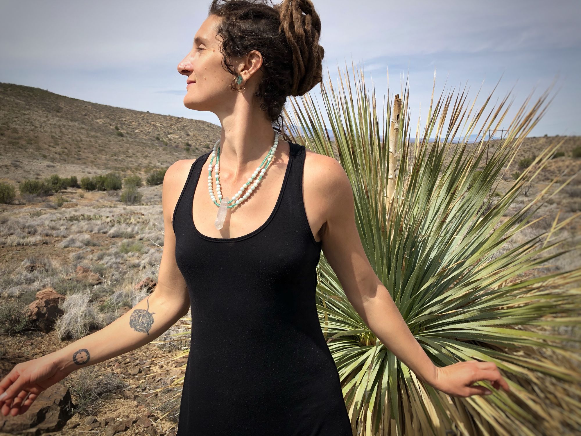 Woman wearing black dress standing by cactus wearing green necklace made of quartz, amazonite and glass beads