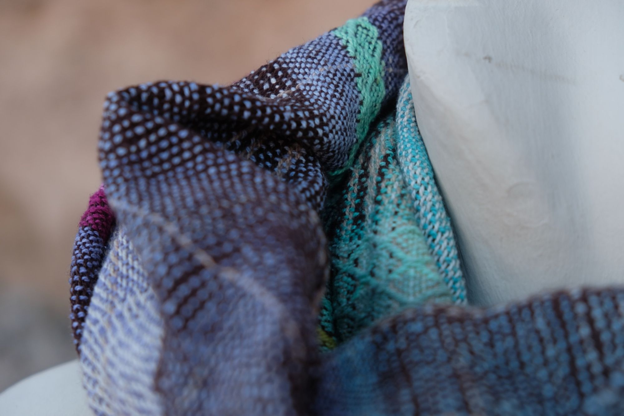 Detail of Blue, pink, yellow, purple and teal handwoven silk scarf on a white mannequin.