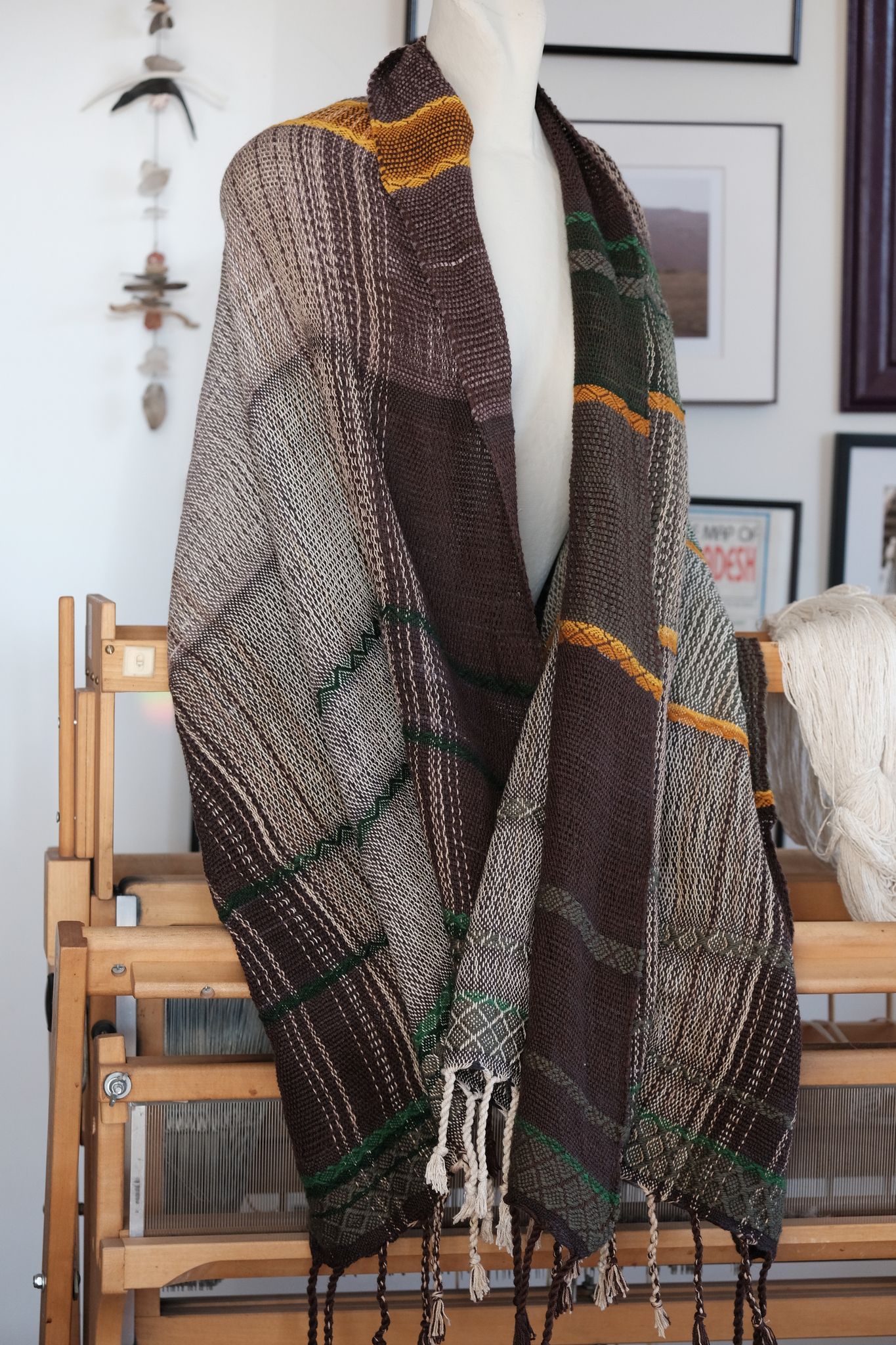 handwoven wool and cotton scarf in green, gold and brown, on a white mannequin