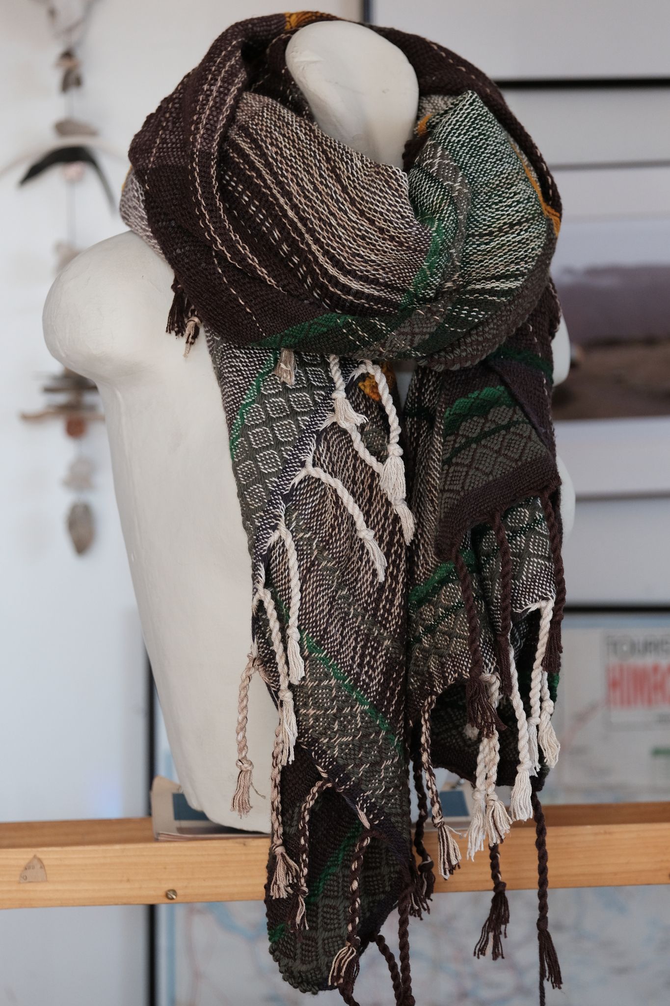 handwoven wool and cotton scarf in green, gold and brown, on a white mannequin