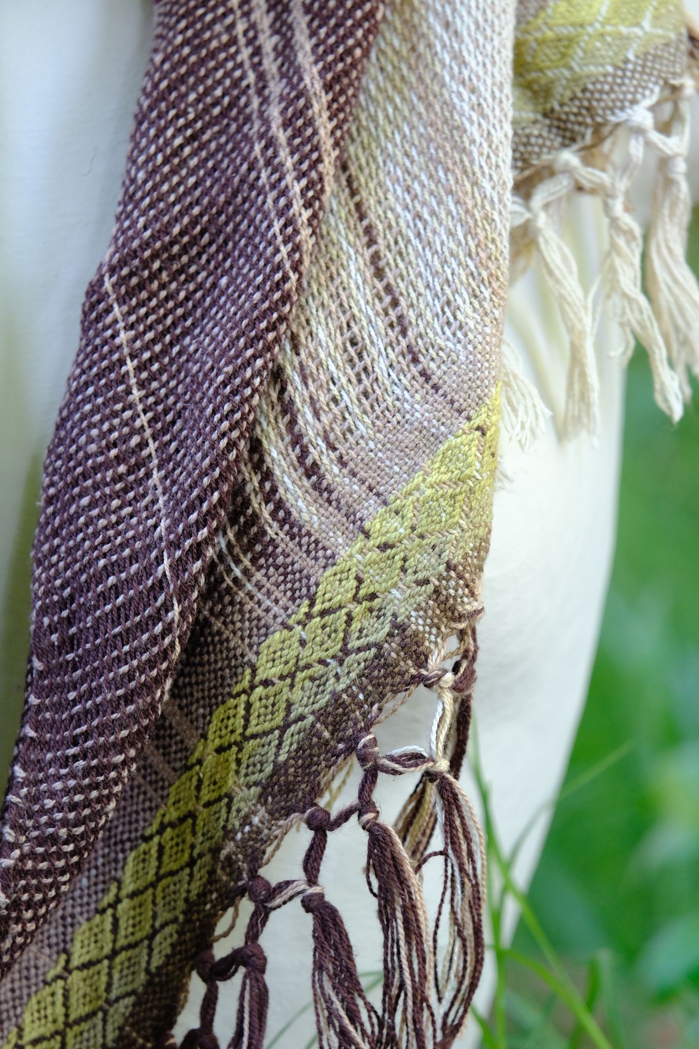 Handwoven naturally dyed brown, green, chartreuse, yellow and pink scarf on a white mannequin