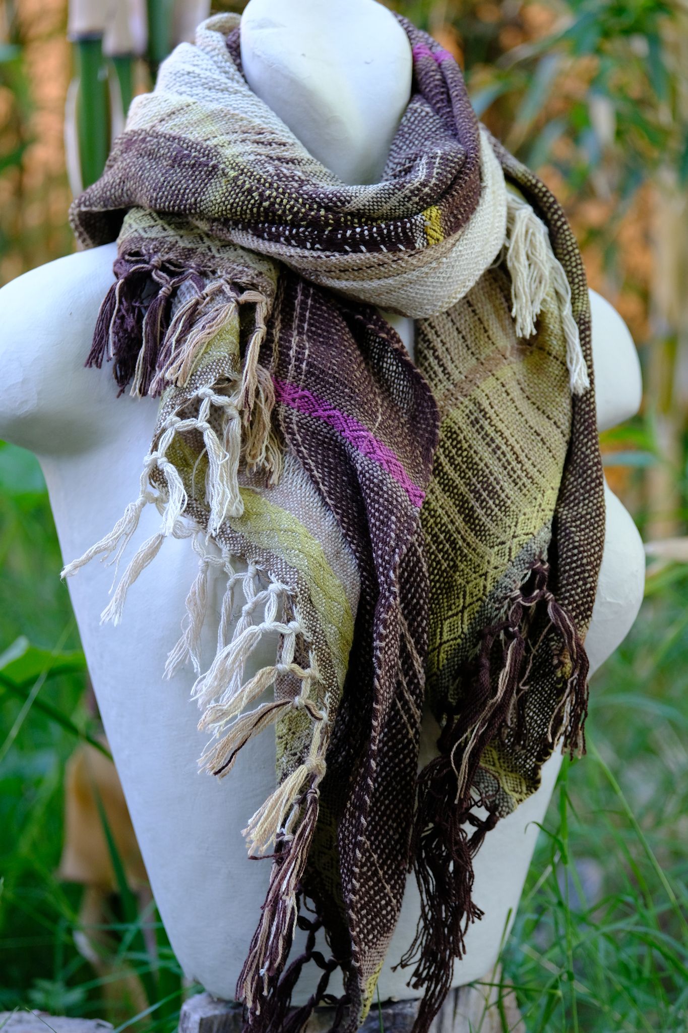 Handwoven naturally dyed brown, green, chartreuse, yellow and pink scarf on a white mannequin