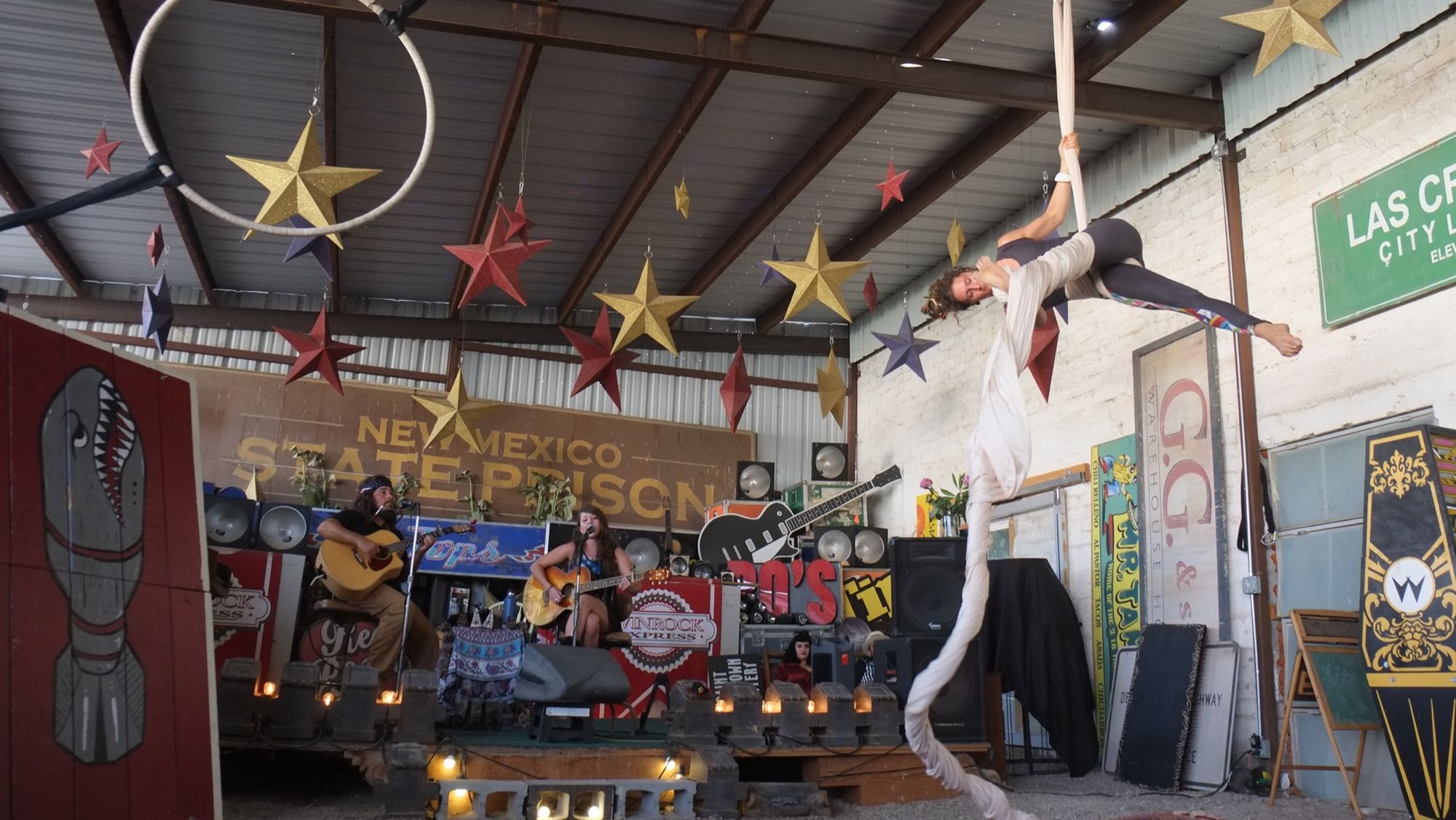 Woman performing aerial silks with live music in a circus like setting