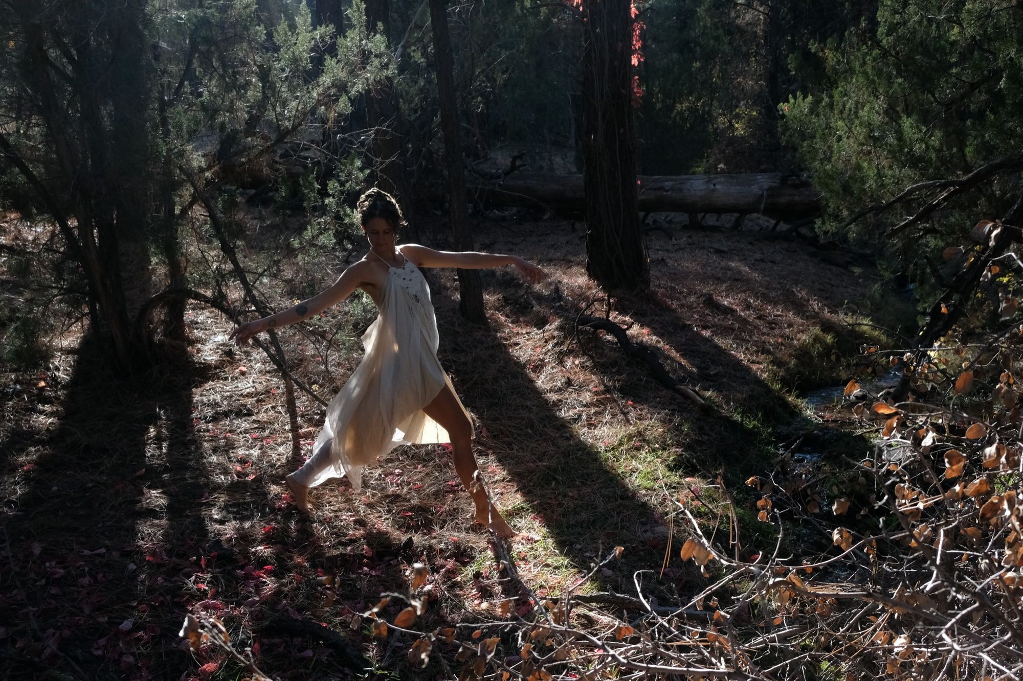 woman wearing white layered silk handmade dress in the forest