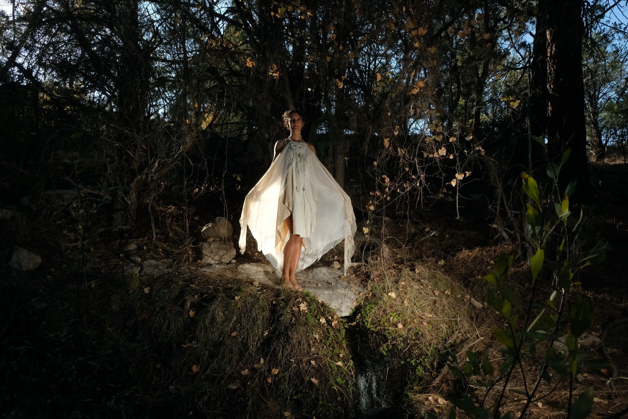 woman wearing white layered silk handmade dress in the forest