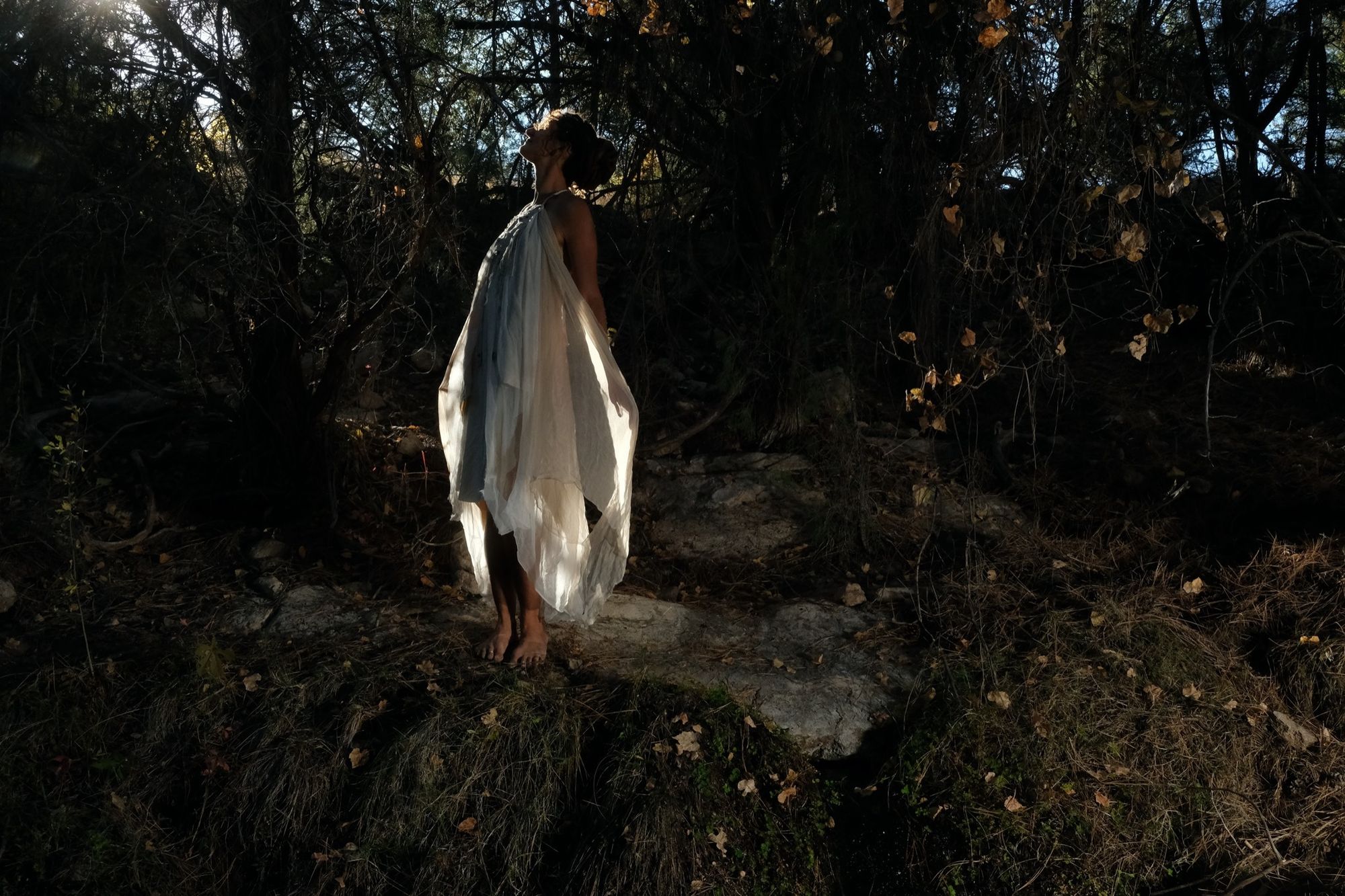 woman wearing white layered silk handmade dress in the forest