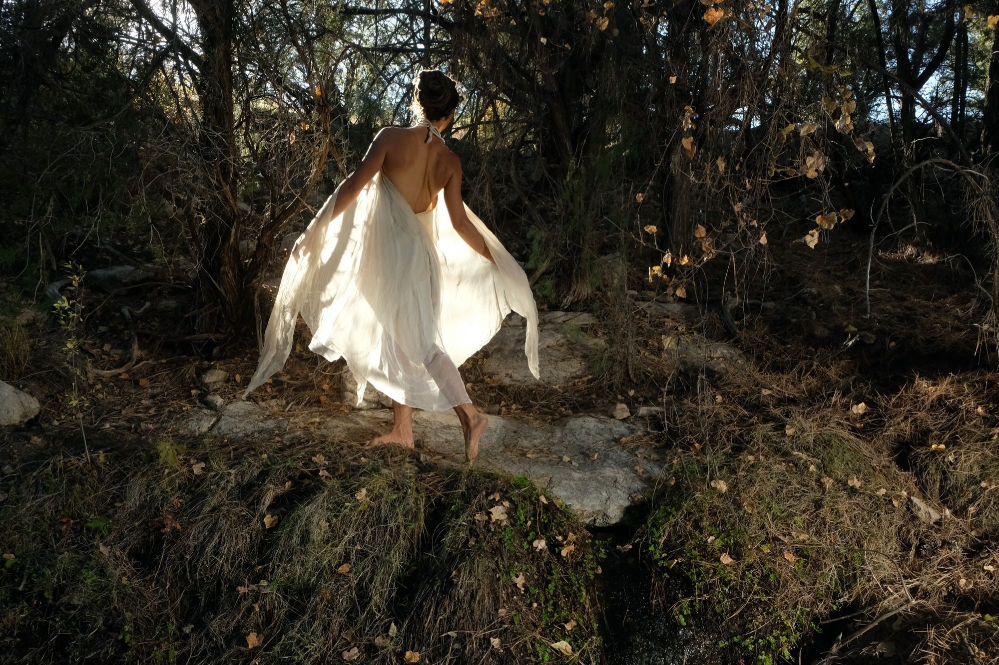 woman wearing white layered silk handmade dress in the forest