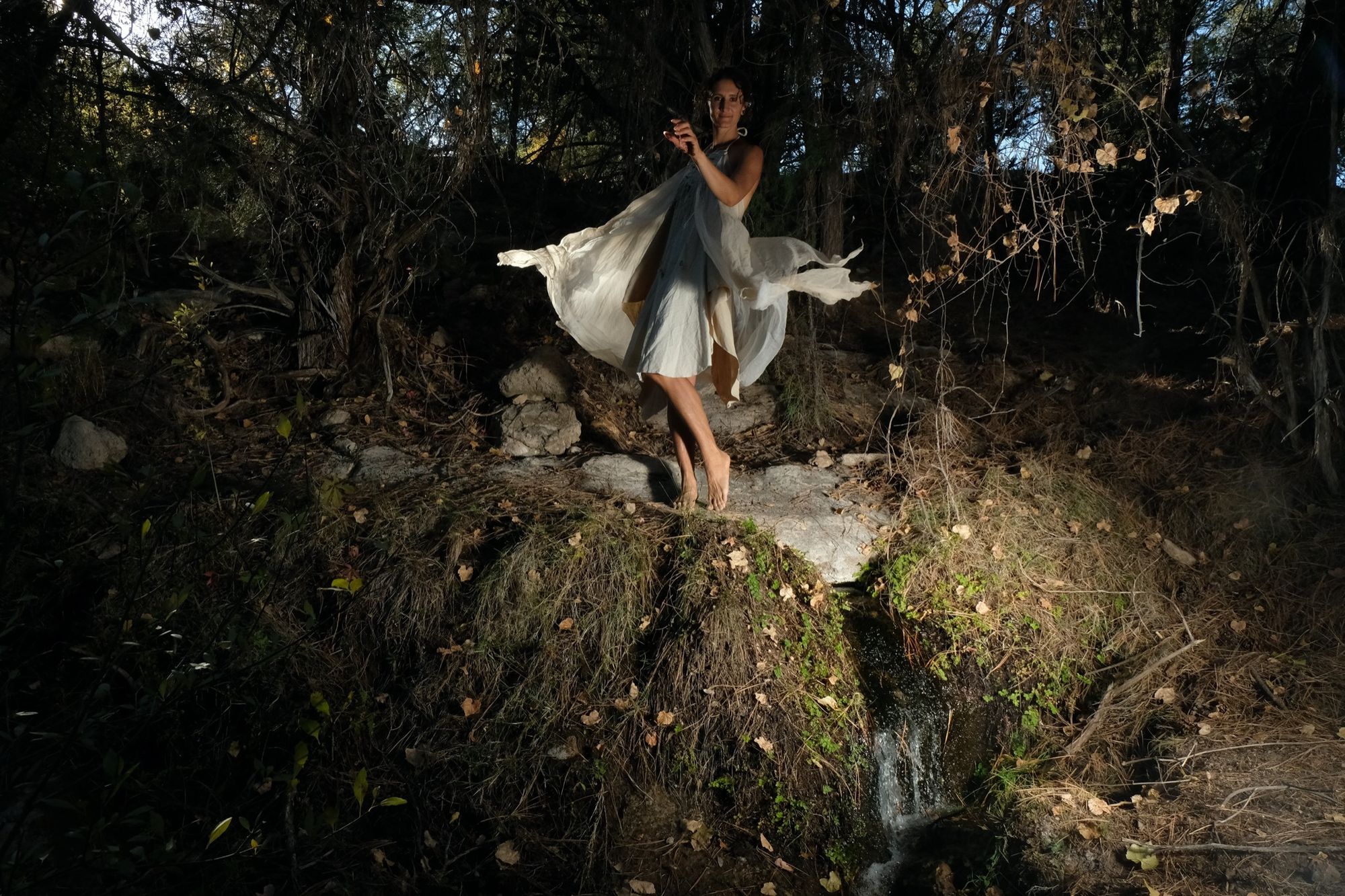 woman wearing white layered silk handmade dress in the forest