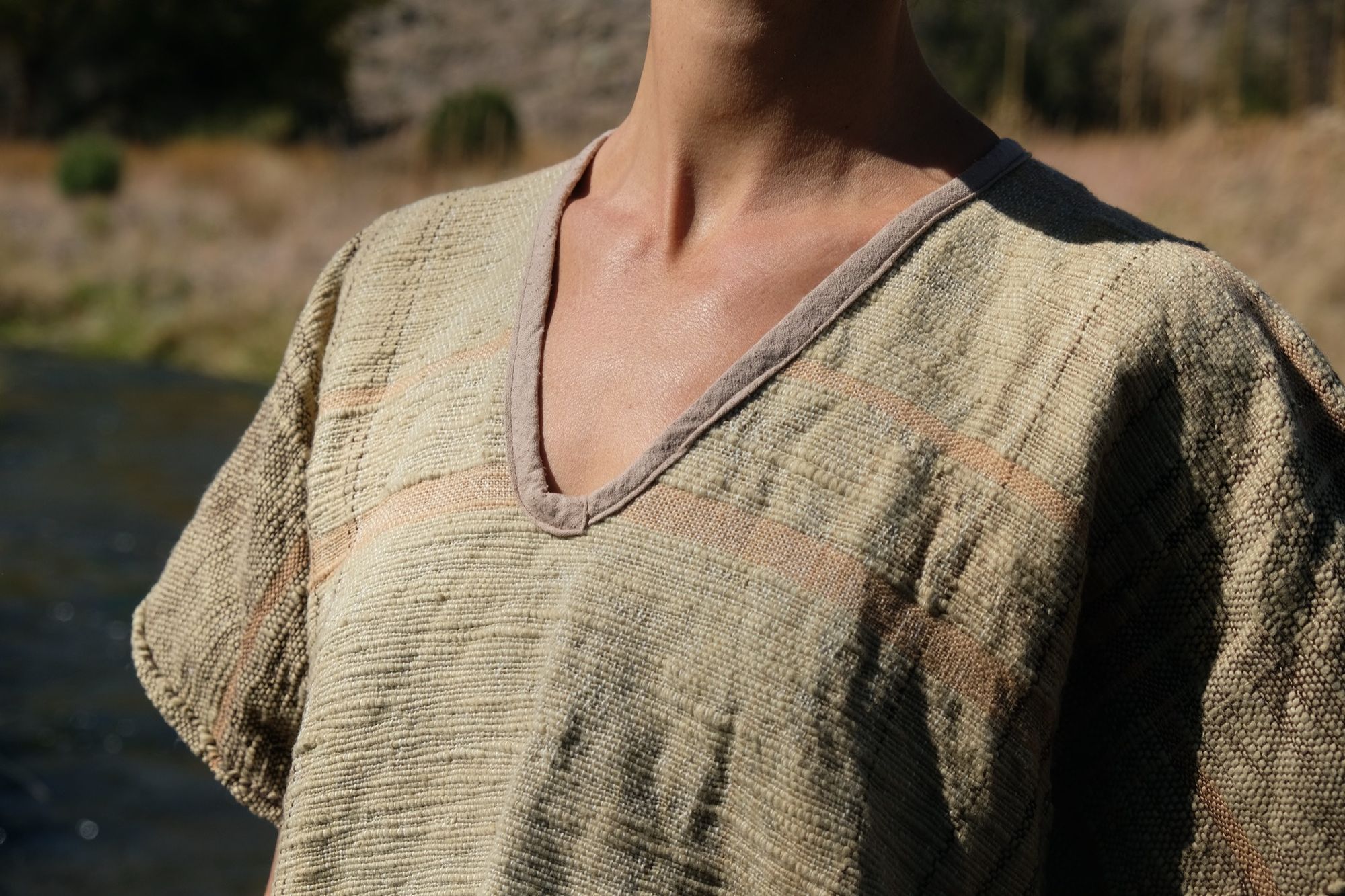 detail of woman wearing tan and dark brown Handspun handwoven Colorgrown Cotton Box Top while standing in a creek