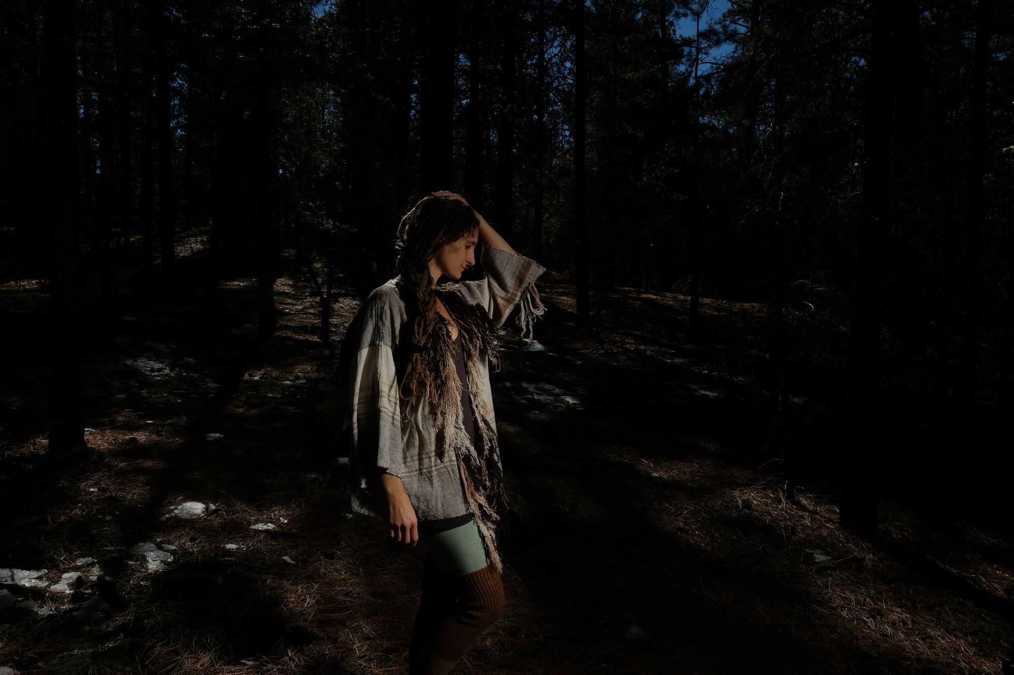 woman wearing raw silk and organic cotton linen brown, tan and white Handwoven fringed Cloak in a dark forest
