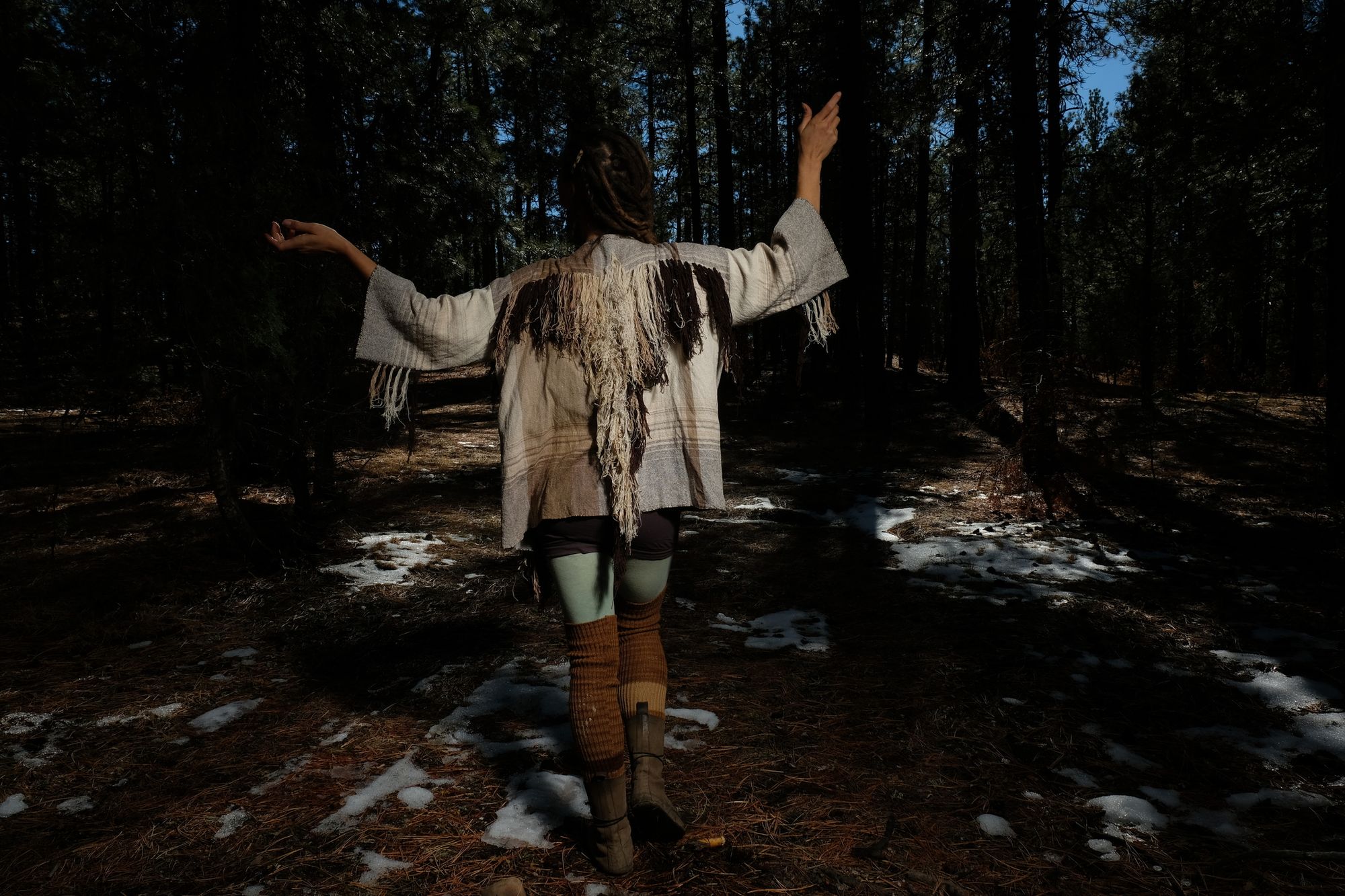 woman wearing raw silk and organic cotton linen brown, tan and white Handwoven fringed Cloak in a dark forest