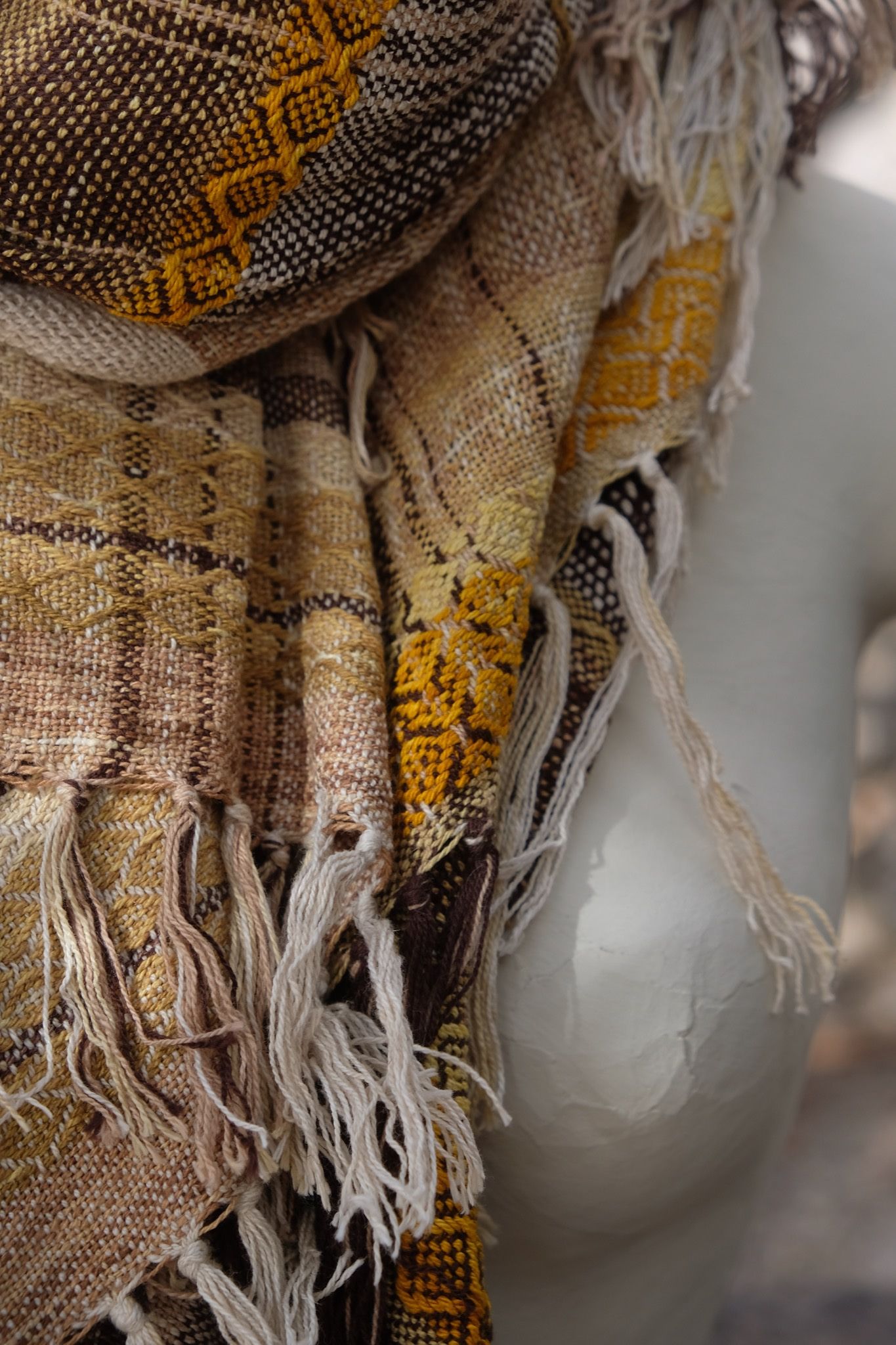 detail of Handwoven raw silk scarf in shades of yellow on a white mannequin