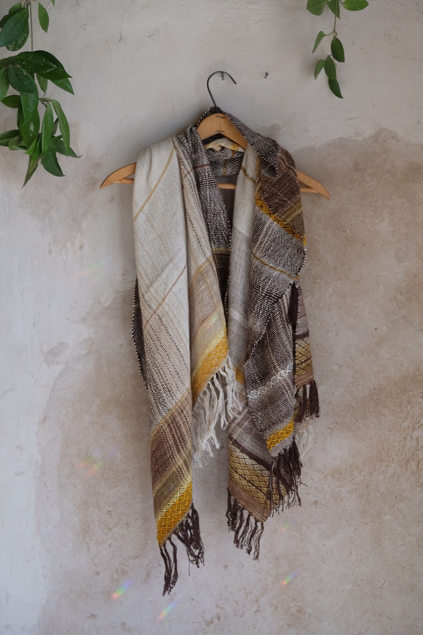 Handwoven raw silk scarf in shades of yellow on a white mannequin