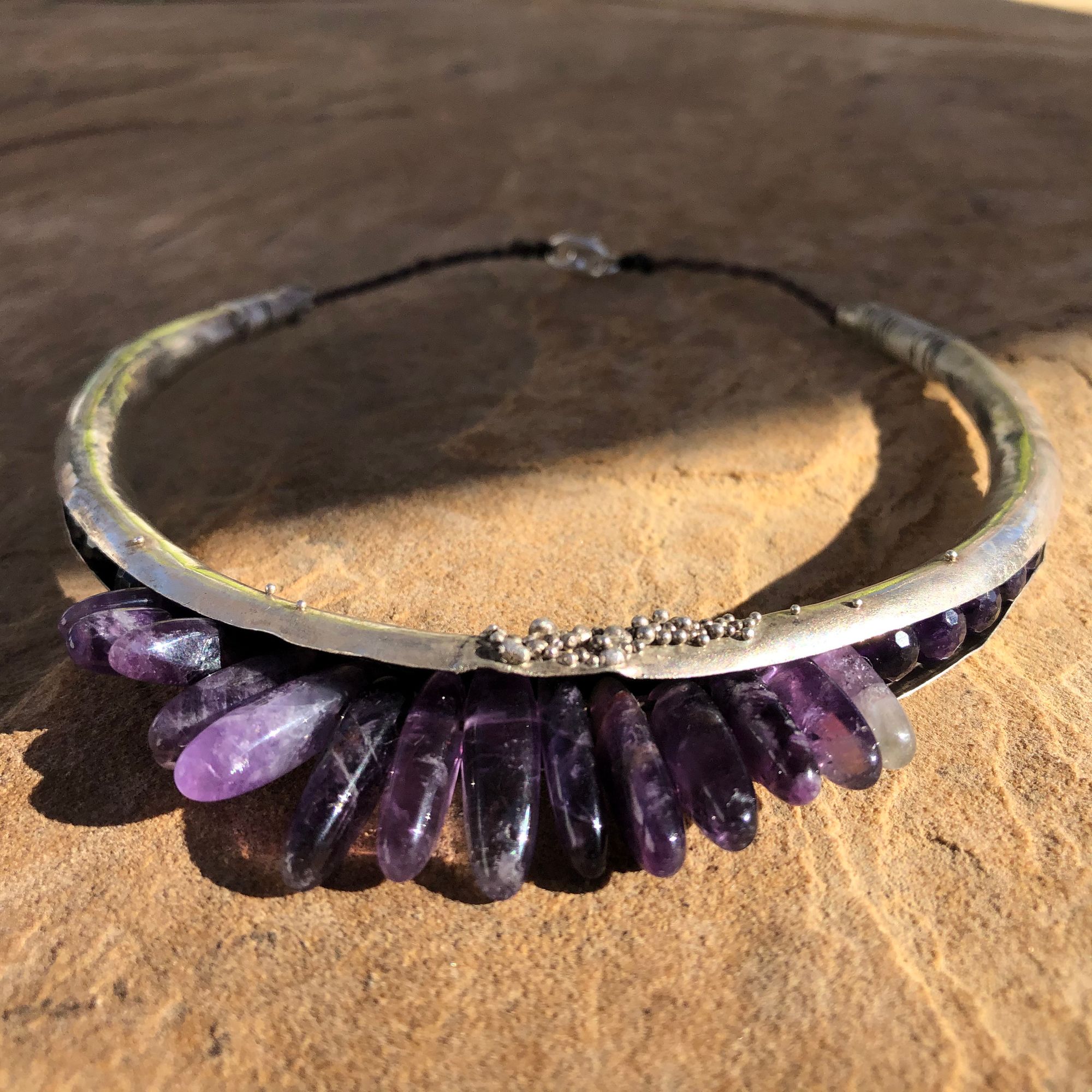 silver hoop necklace with purple amethyst spears protruding from the bottom.