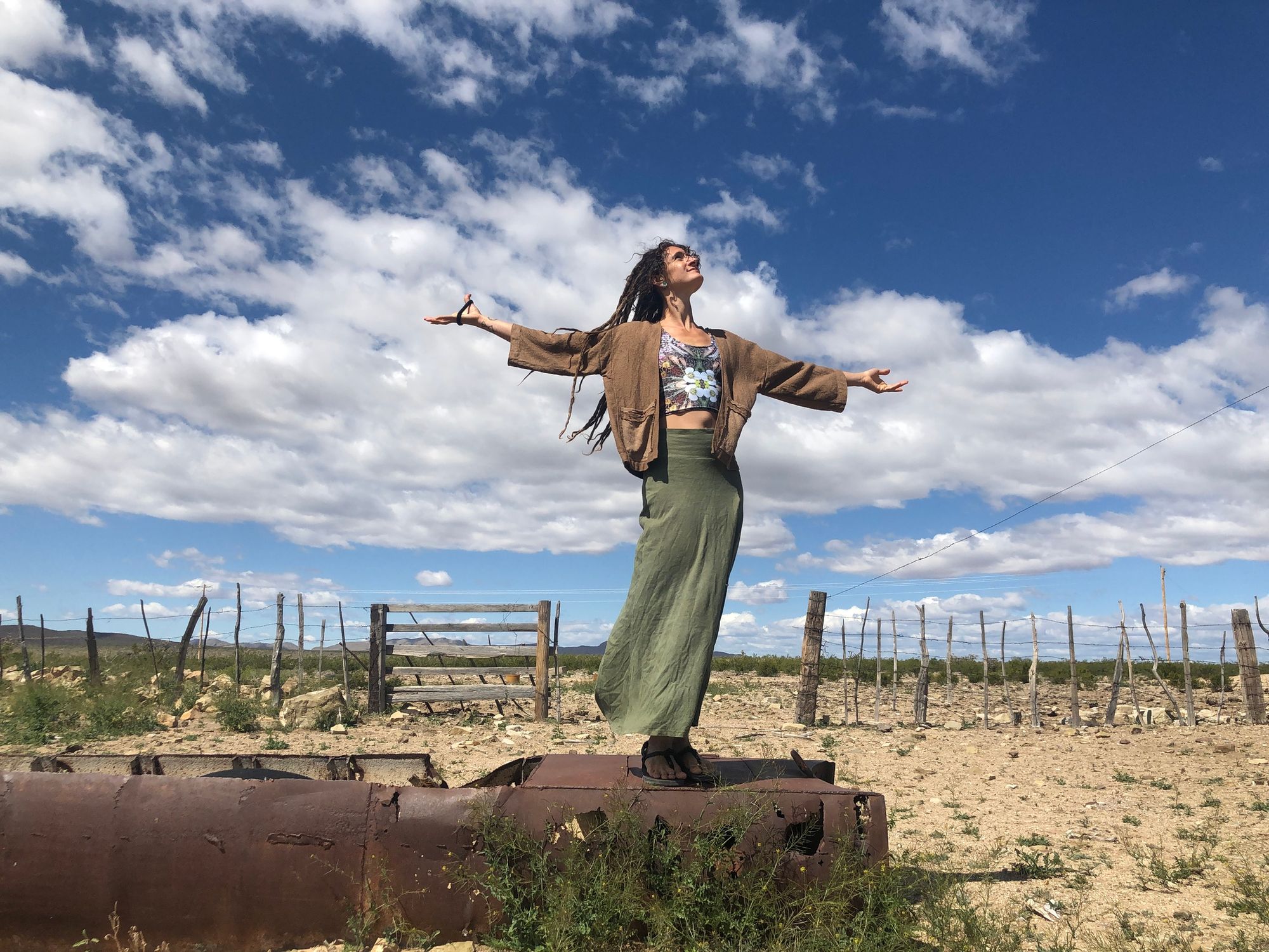 woman wearing handmade brown jacket and green skirt, standing in the desert