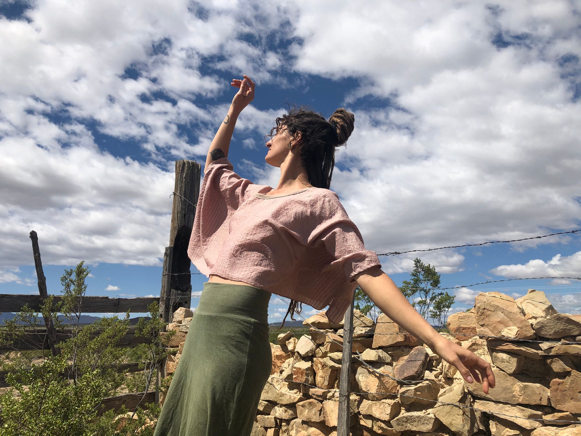 woman wearing Pink striped hand sewn silk shirt and green skirt outside with a blue cloudy sky