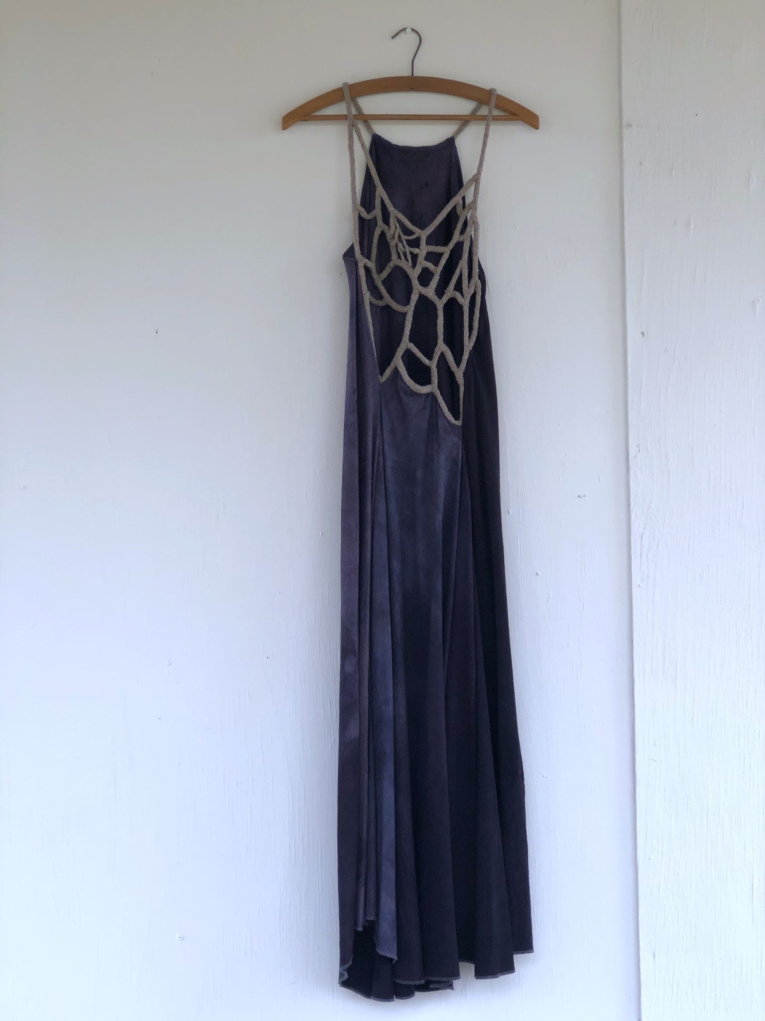 blue and grey dress hanging on a hanger on a white wall
