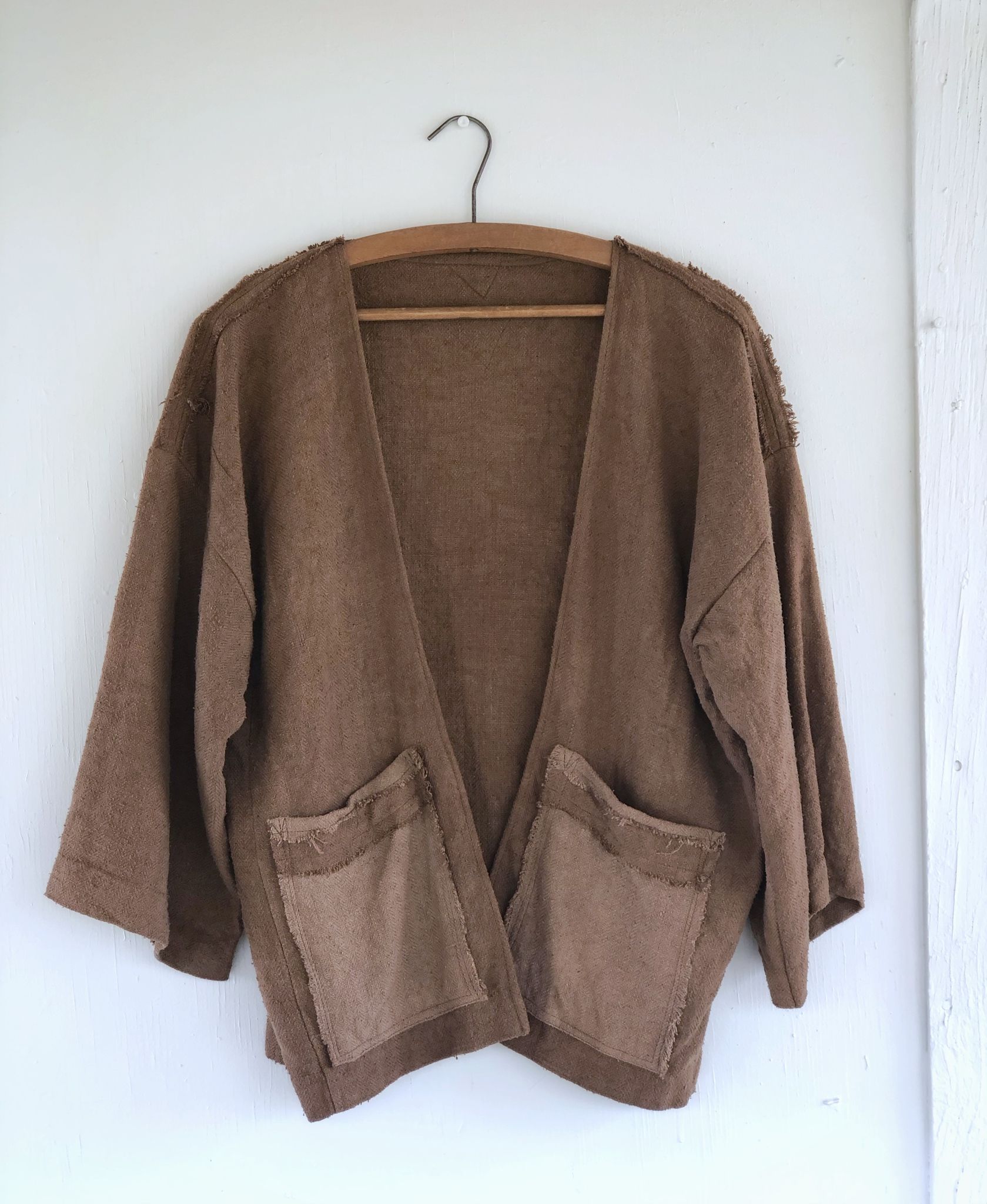 detail of handmade brown jacket with large pockets hanging on a hanger