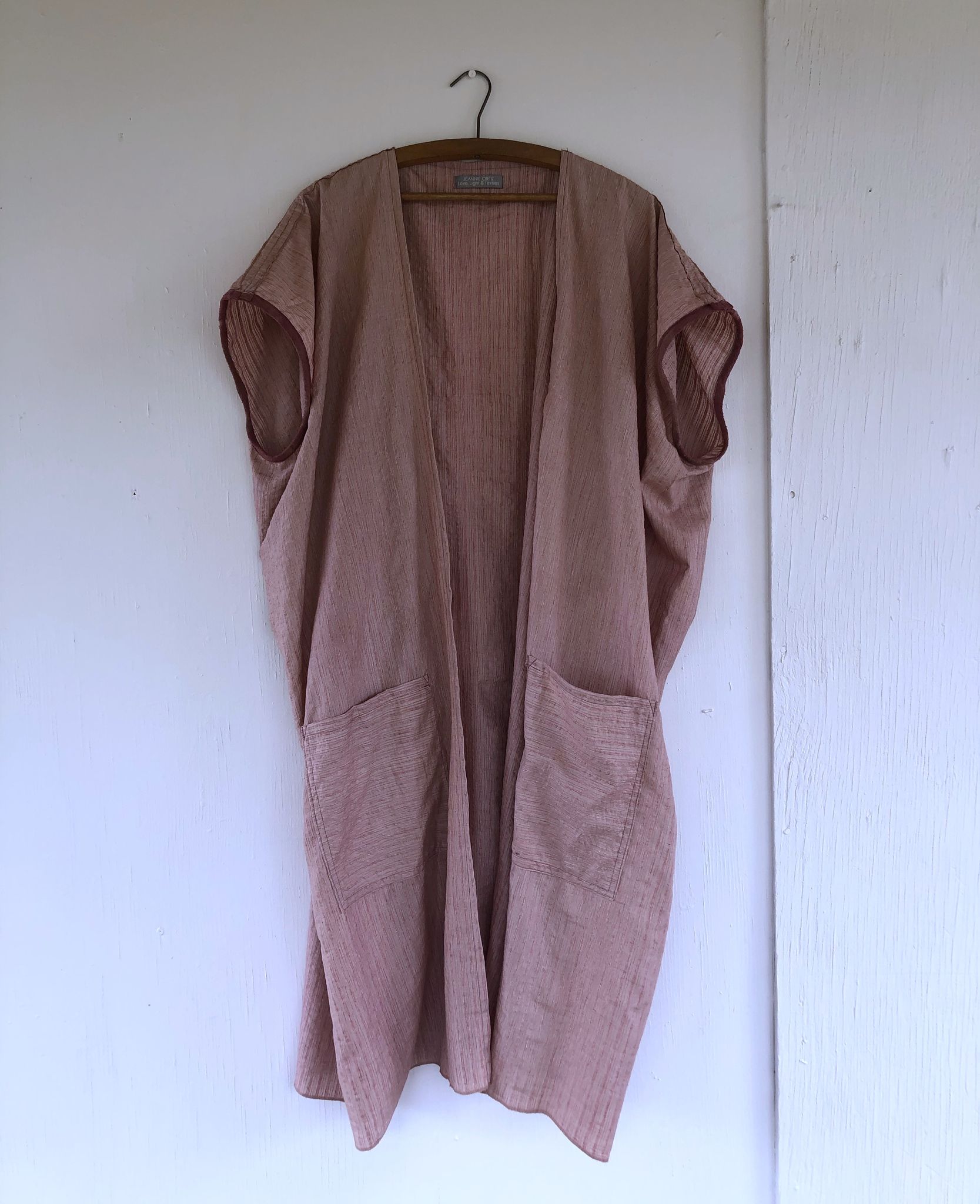 Hand Sewn pink striped Silk Cloak on a hanger on a white wall