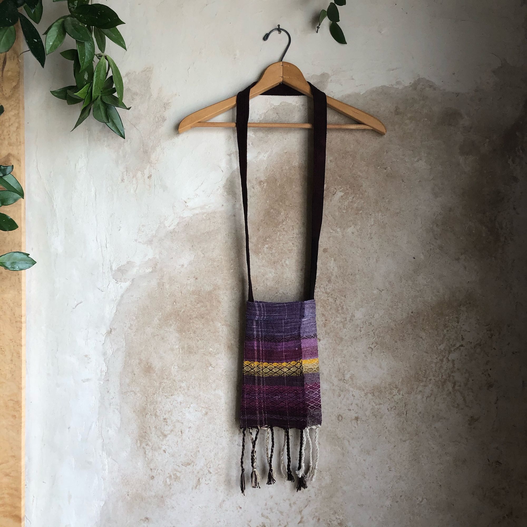 Simple Little Handwoven pink, yellow and purple raw silk Bag on a hanger, on a tan adobe wall