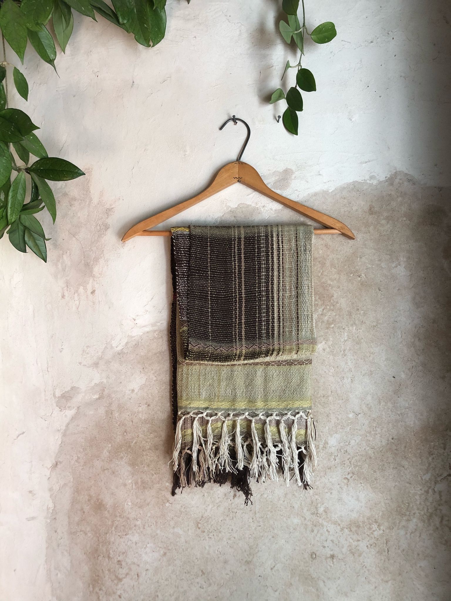 Handwoven naturally dyed brown, green, chartreuse, yellow and pink scarf on a hanger