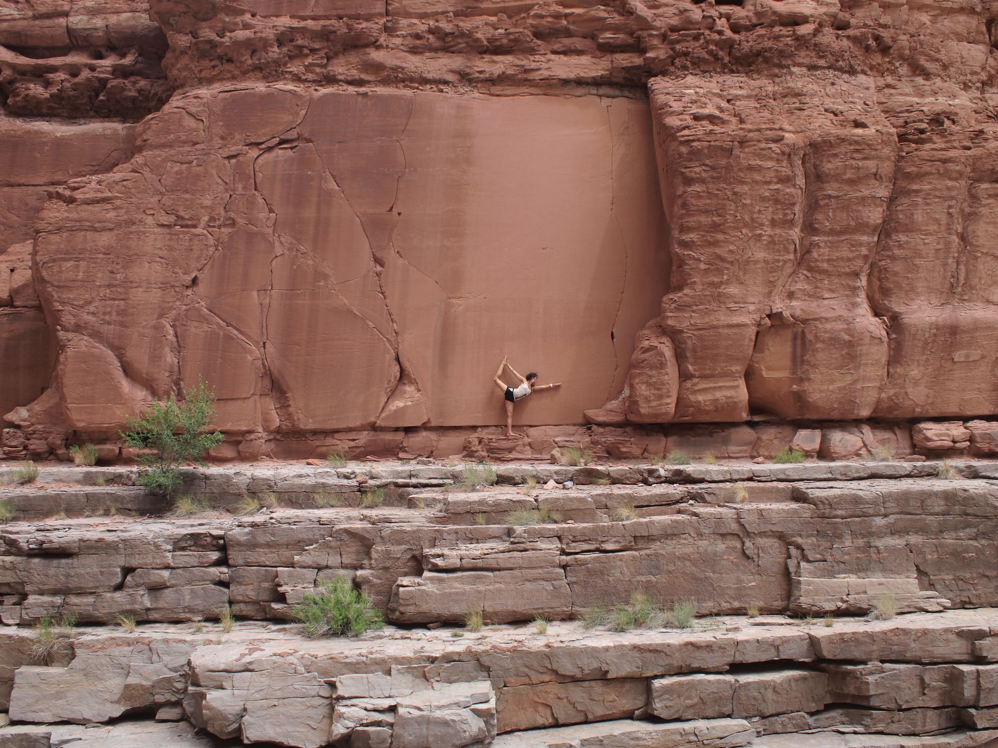 Woman doing yoga against against a red sandstone canyon wall