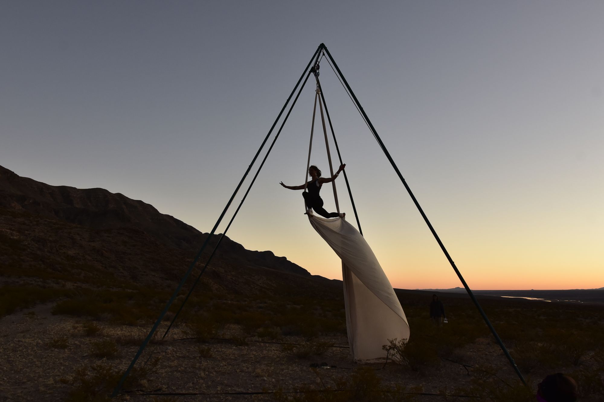 Woman silhouetted at sunset doing aerial acrobatics in the mountains 