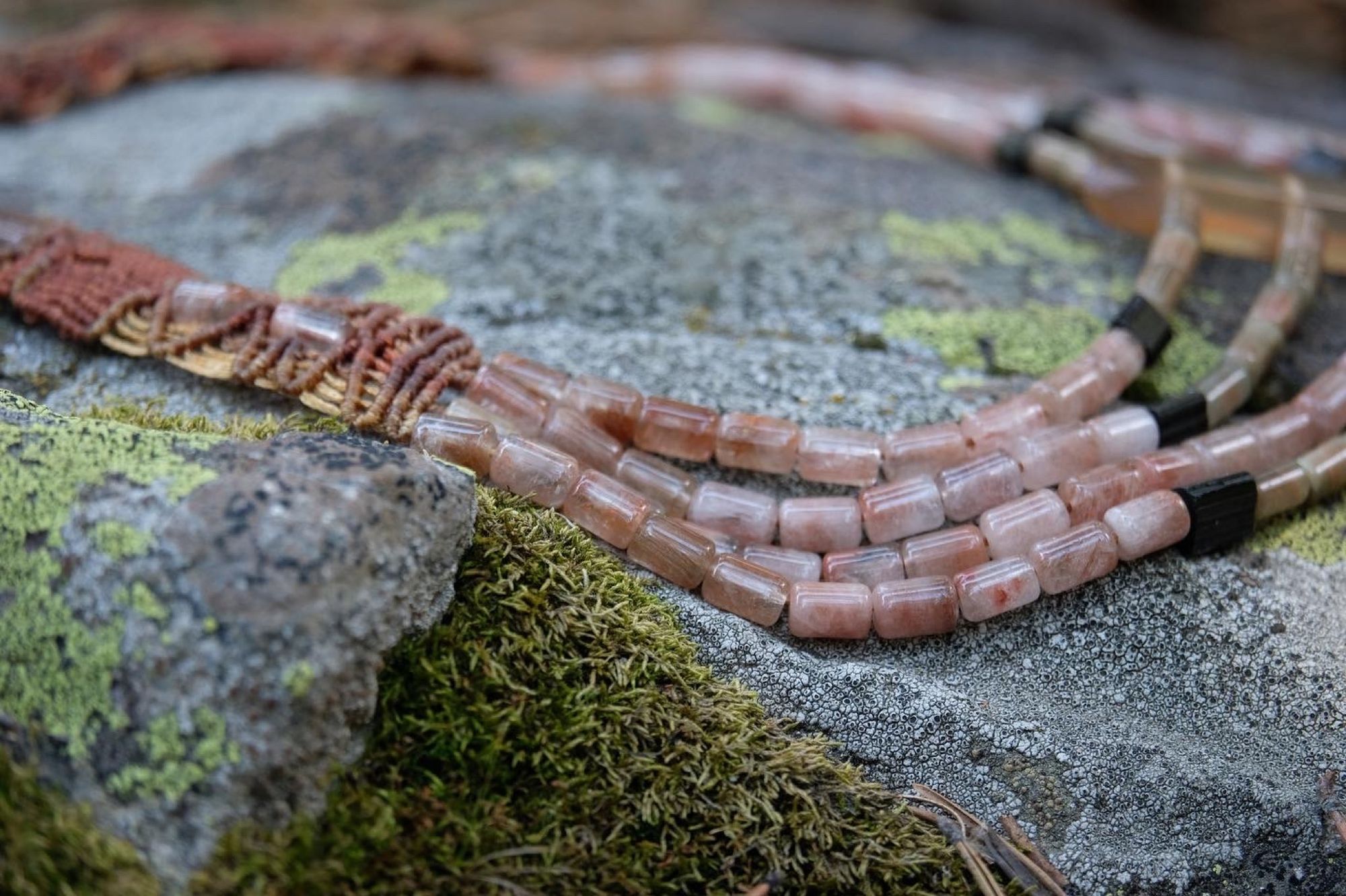 Four strand Zambian citrine, pink Rutilated quartz and black tourmaline necklace laying on a mossy rock