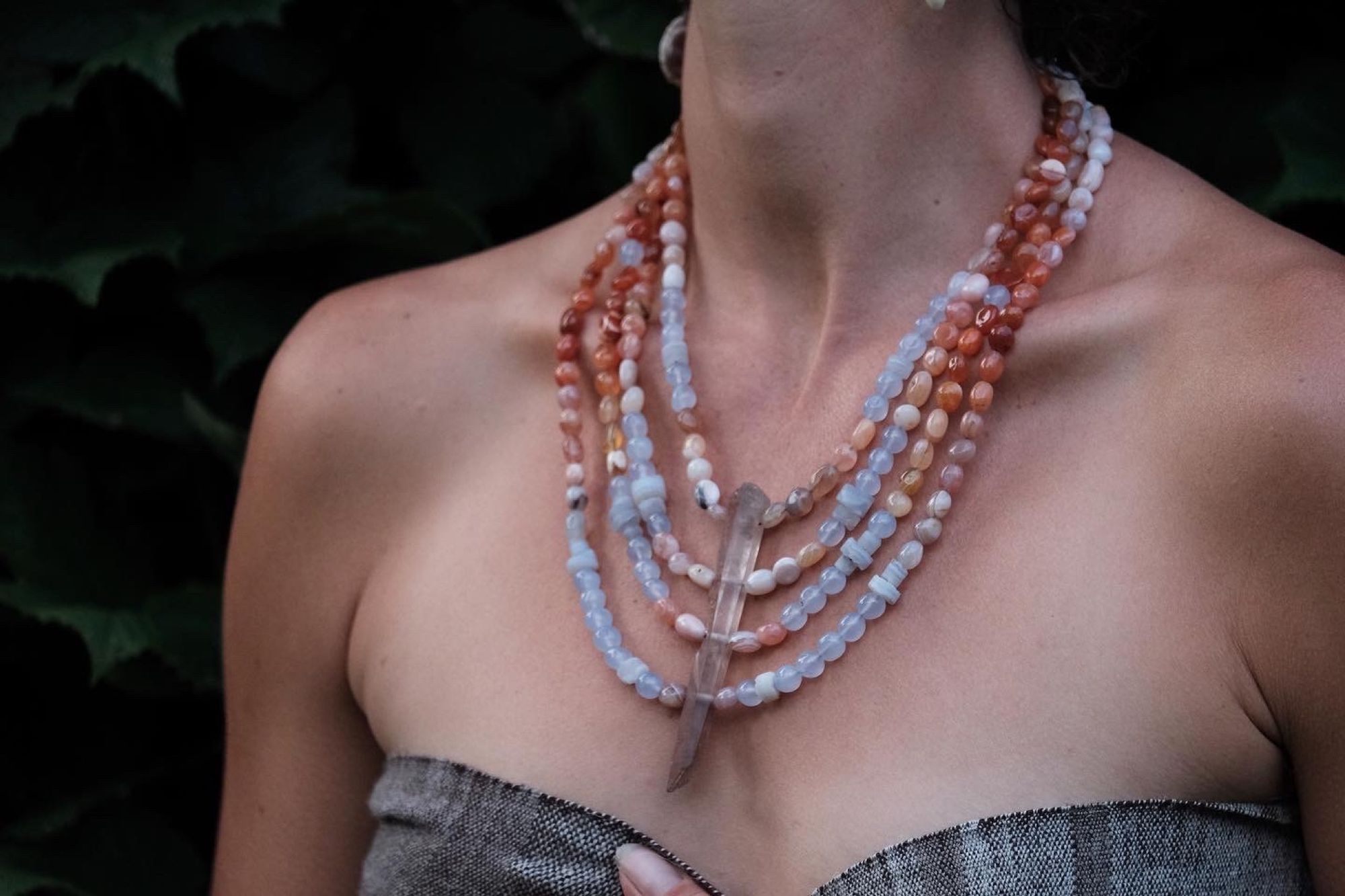 woman wearing clear quartz point, red-pink-white graded Botswana agate and blue chalcedony necklace 