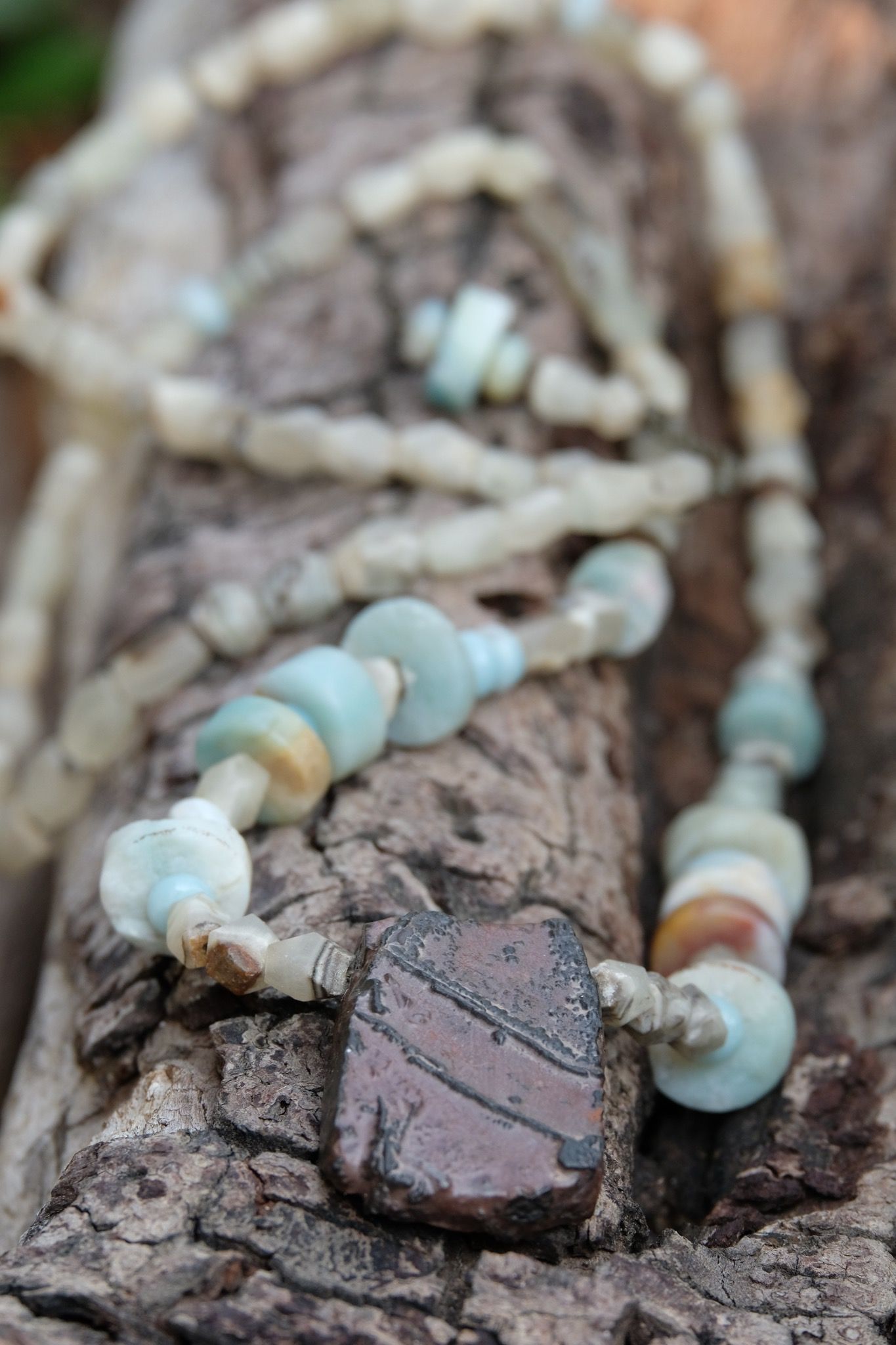 Detail of Tsesit, Afghan Jade and Amazonite adornment resting on a branch