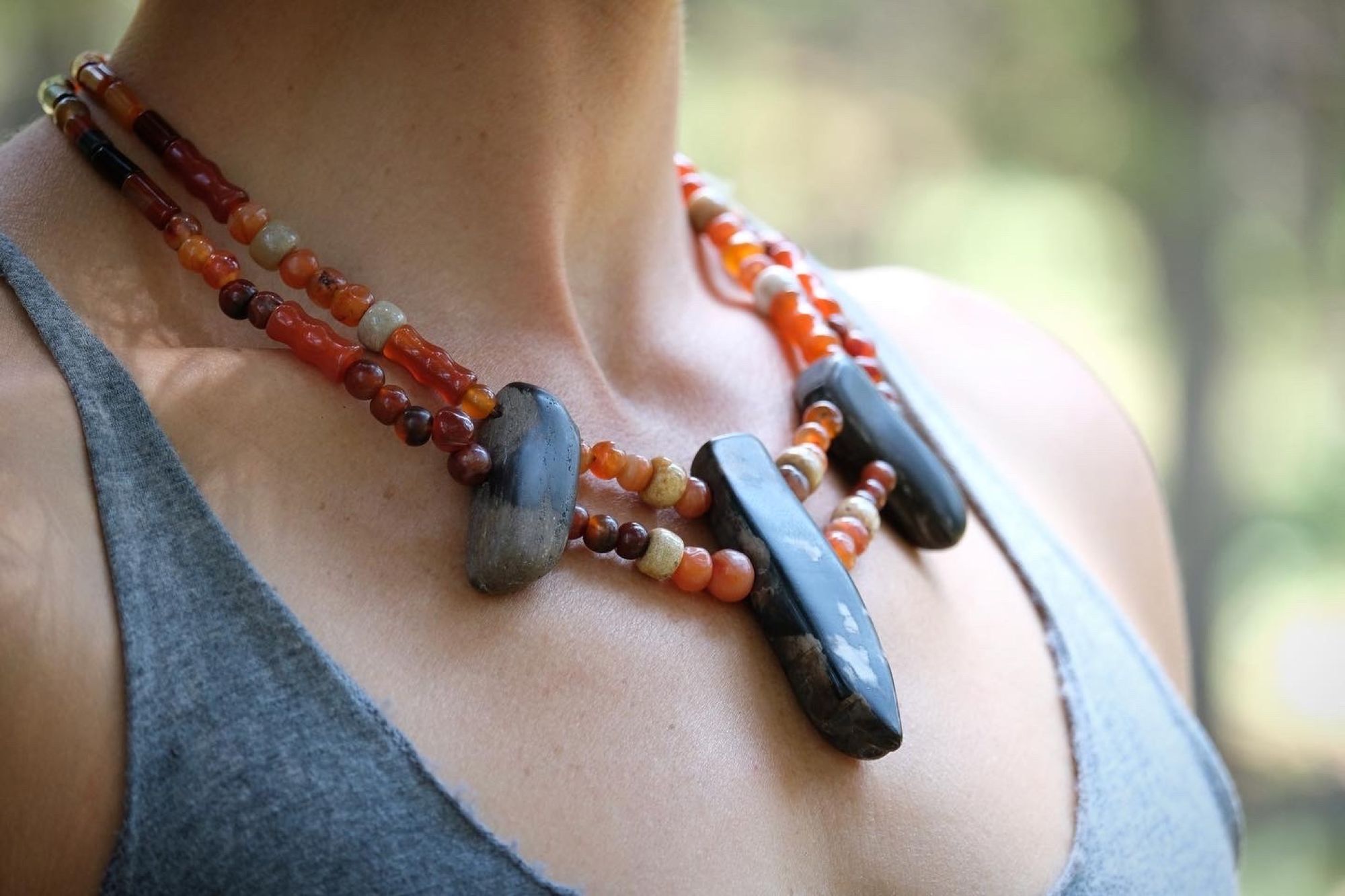 woman wearing dark petrified wood, tan fossilized coral and red orange carnelian necklace