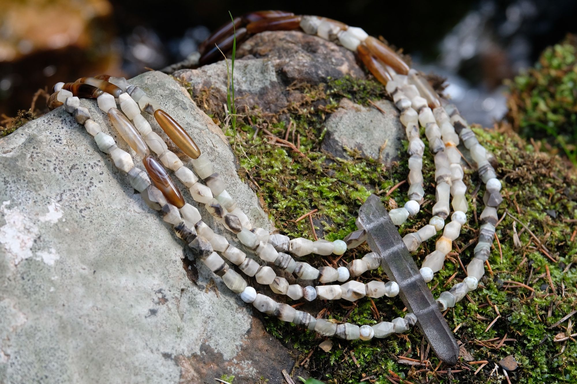 Detail of four strand tan, green and brown faceted jade and quartz point necklace