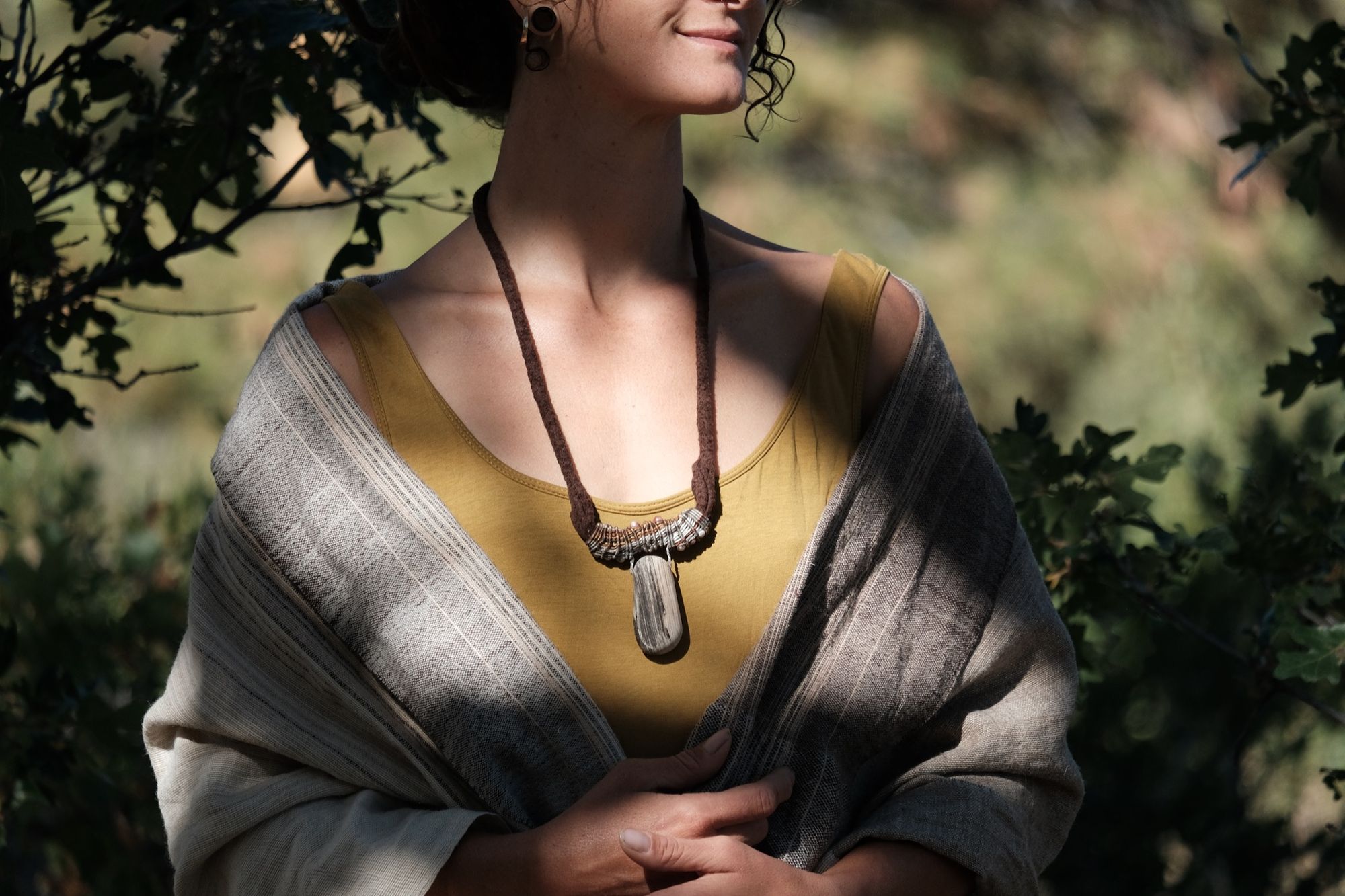 Woman wearing chartreuse shirt and sculptural necklace made of brown felt, petrified wood and grey-brown knotwork