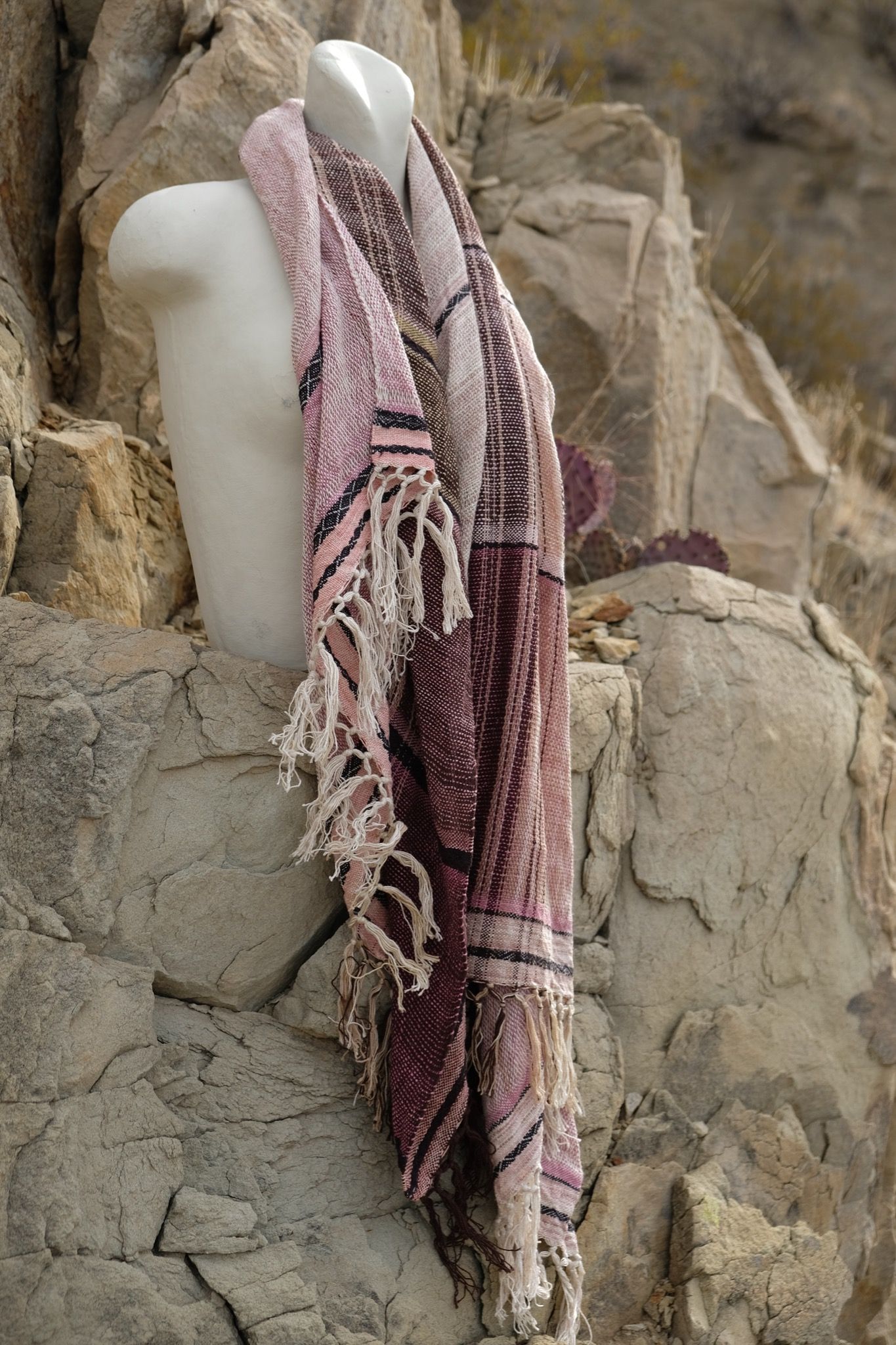 pink, black and white cotton and silks scarf with fringe on a white mannequin bust in the desert