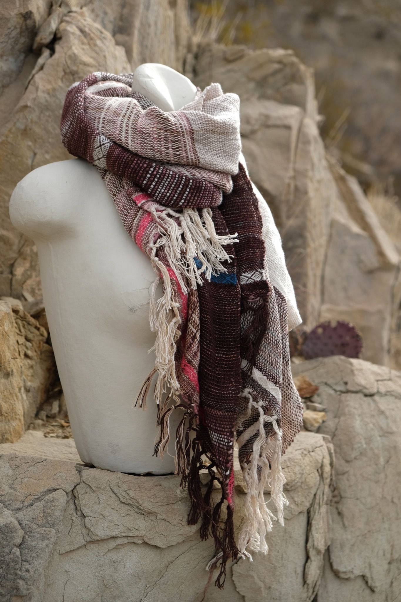 Pink, blue, maroon, white and brown handwoven textured scarf on a white mannequin in the desert 