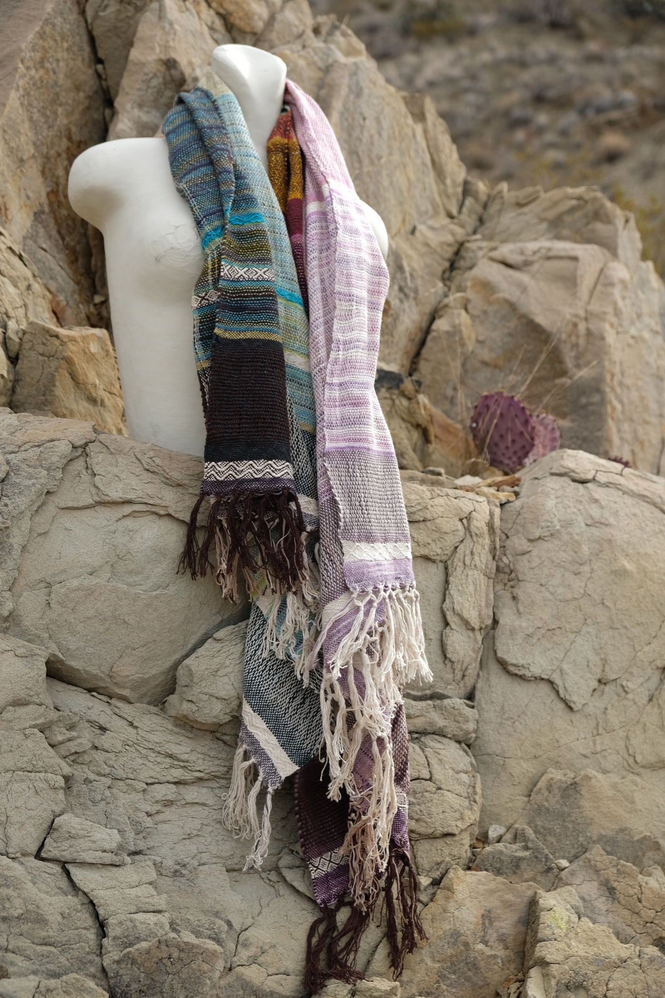 Pink, green, yellow, blue, white, orange and brown handwoven textured scarf on a white mannequin in the desert 