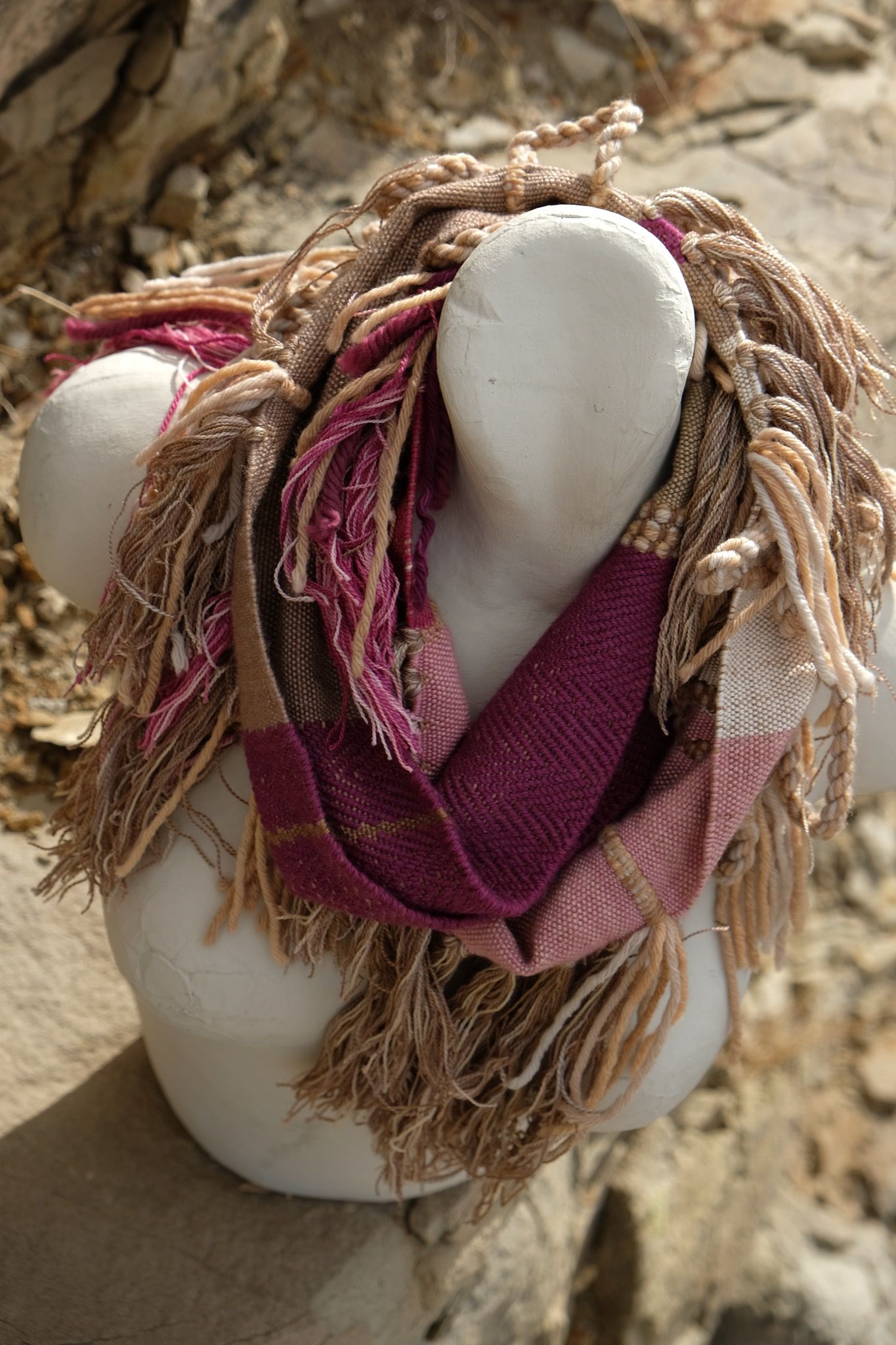 naturally dyed brown, fuchsia and tan fringed infinity scarf on a white mannequin bust in the desert