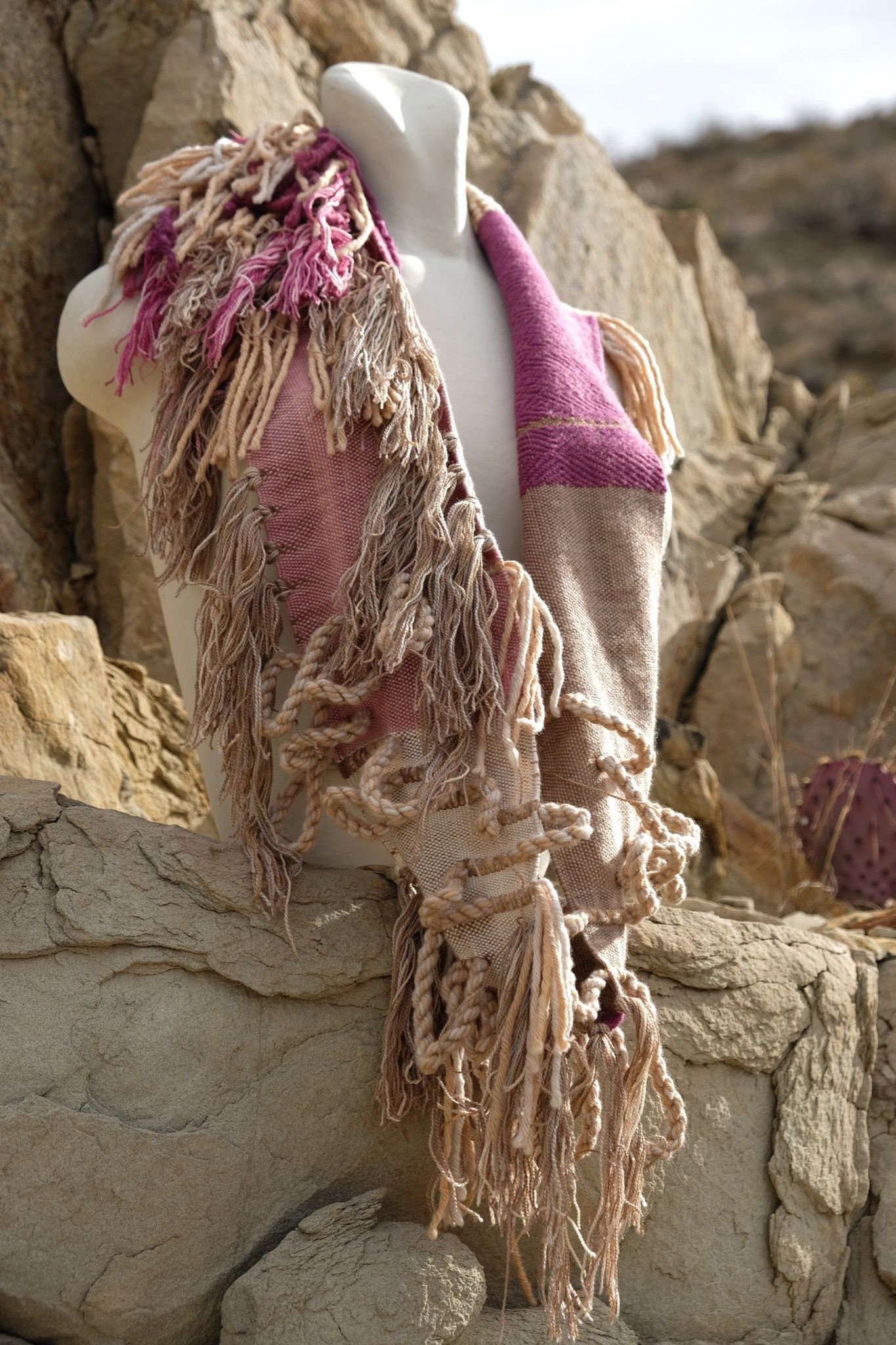 naturally dyed brown, fuchsia and tan fringed infinity scarf on a white mannequin bust in the desert