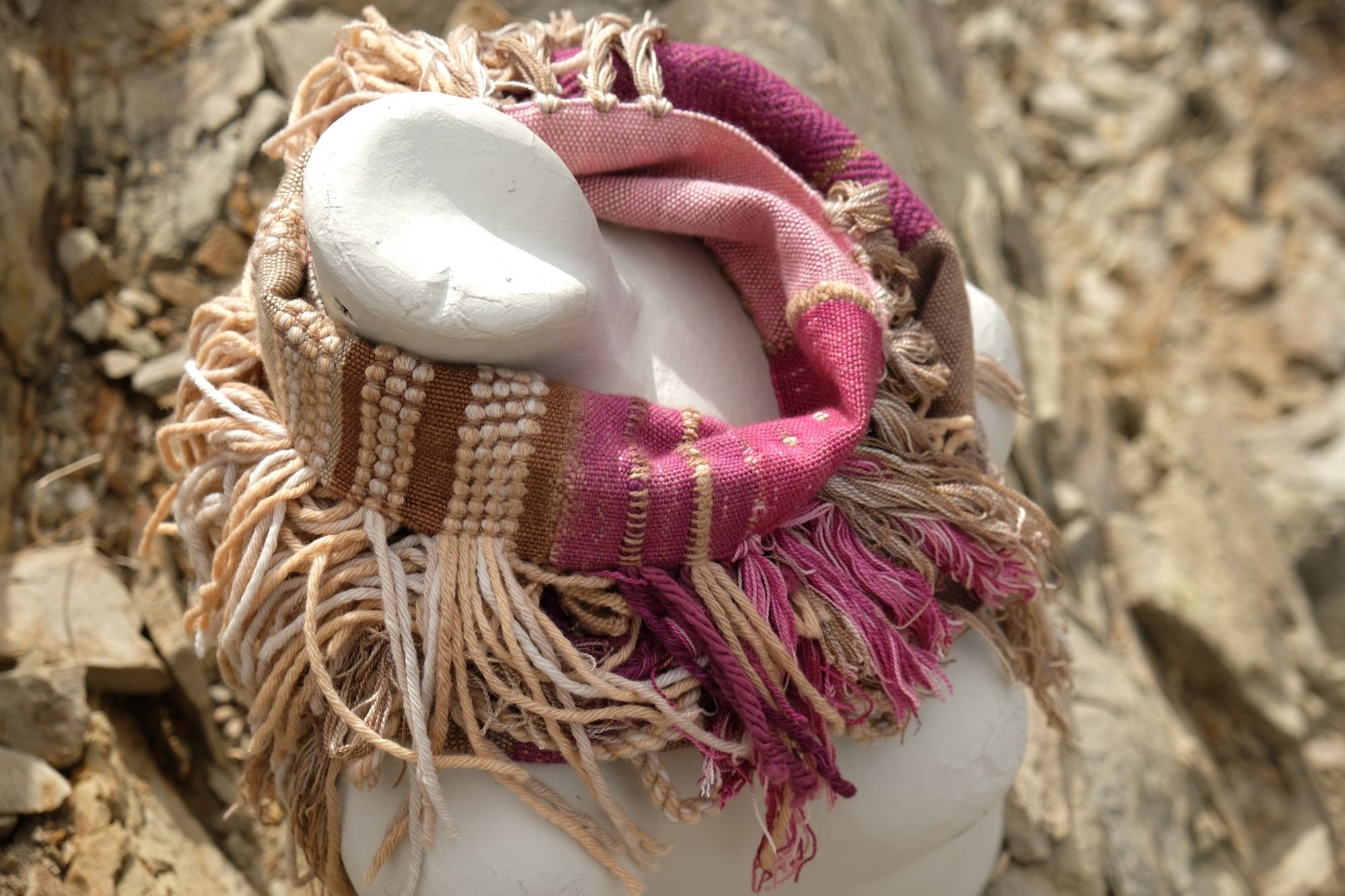 naturally dyed brown, fuchsia and tan fringed infinity scarf on a white mannequin bust in the desert