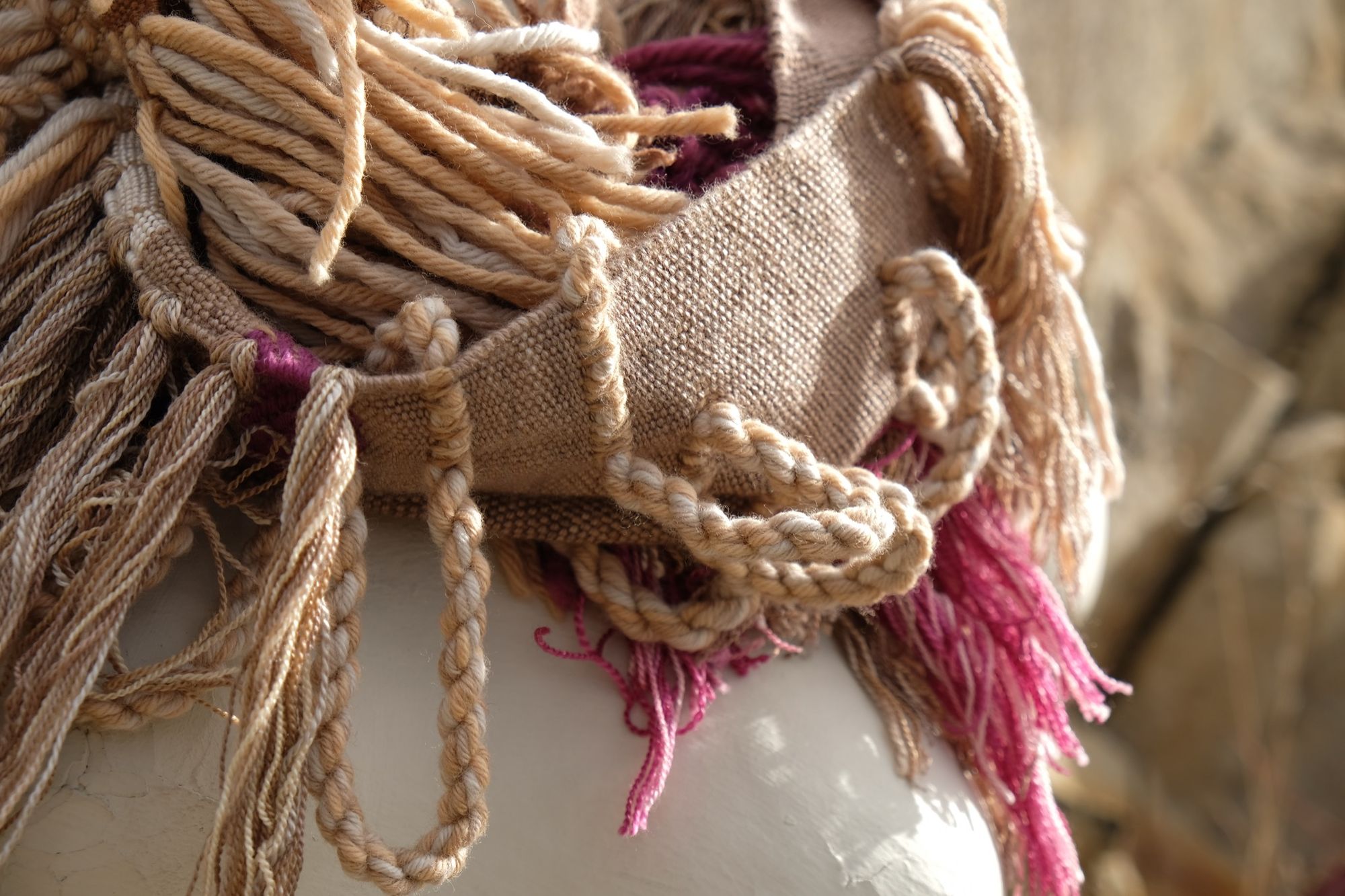 naturally dyed brown, fuchsia and tan fringed infinity scarf on a white mannequin bust in the desert