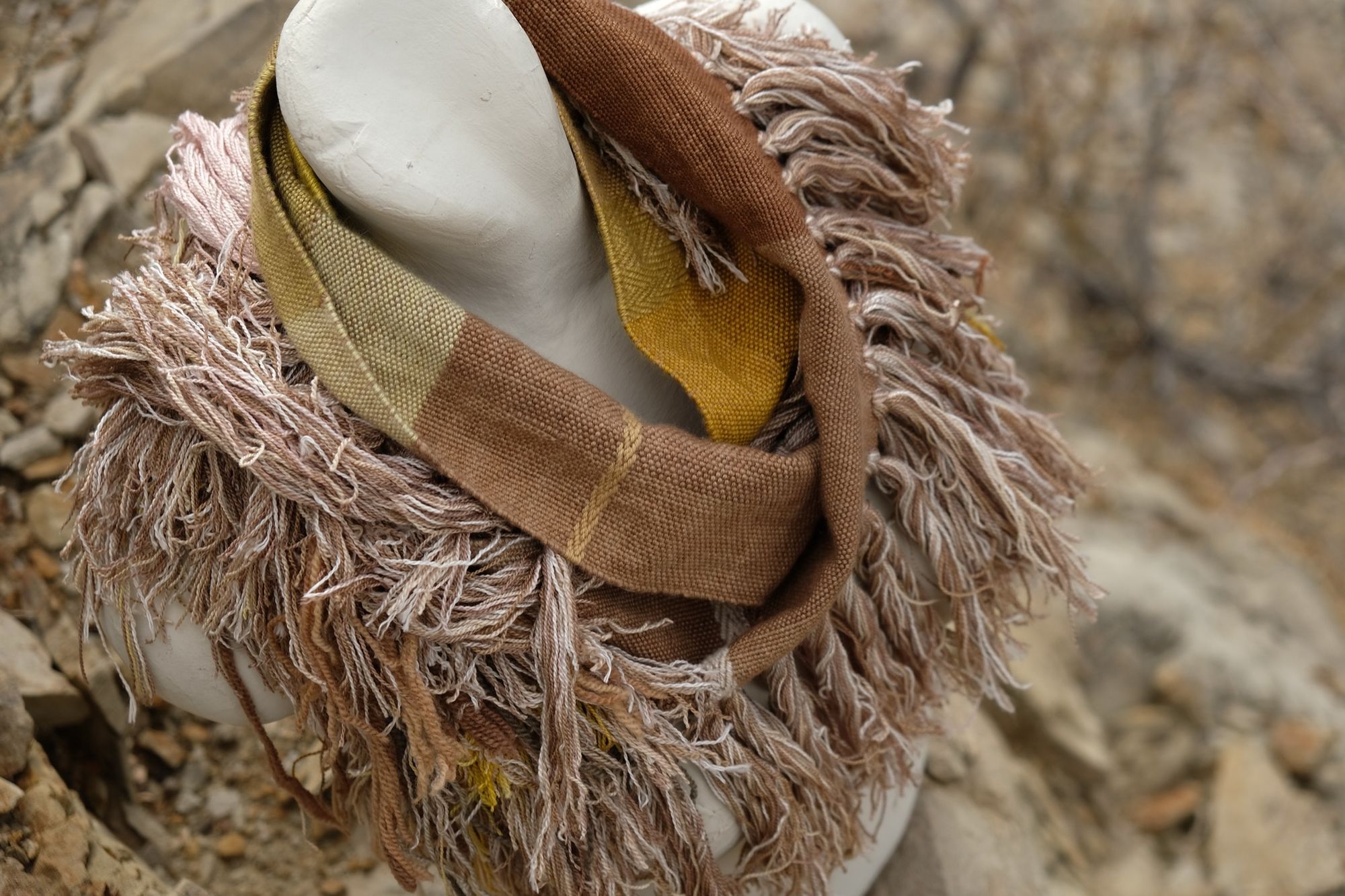 naturally dyed brown, golden yellow and tan fringed infinity scarf on a white mannequin bust in the desert