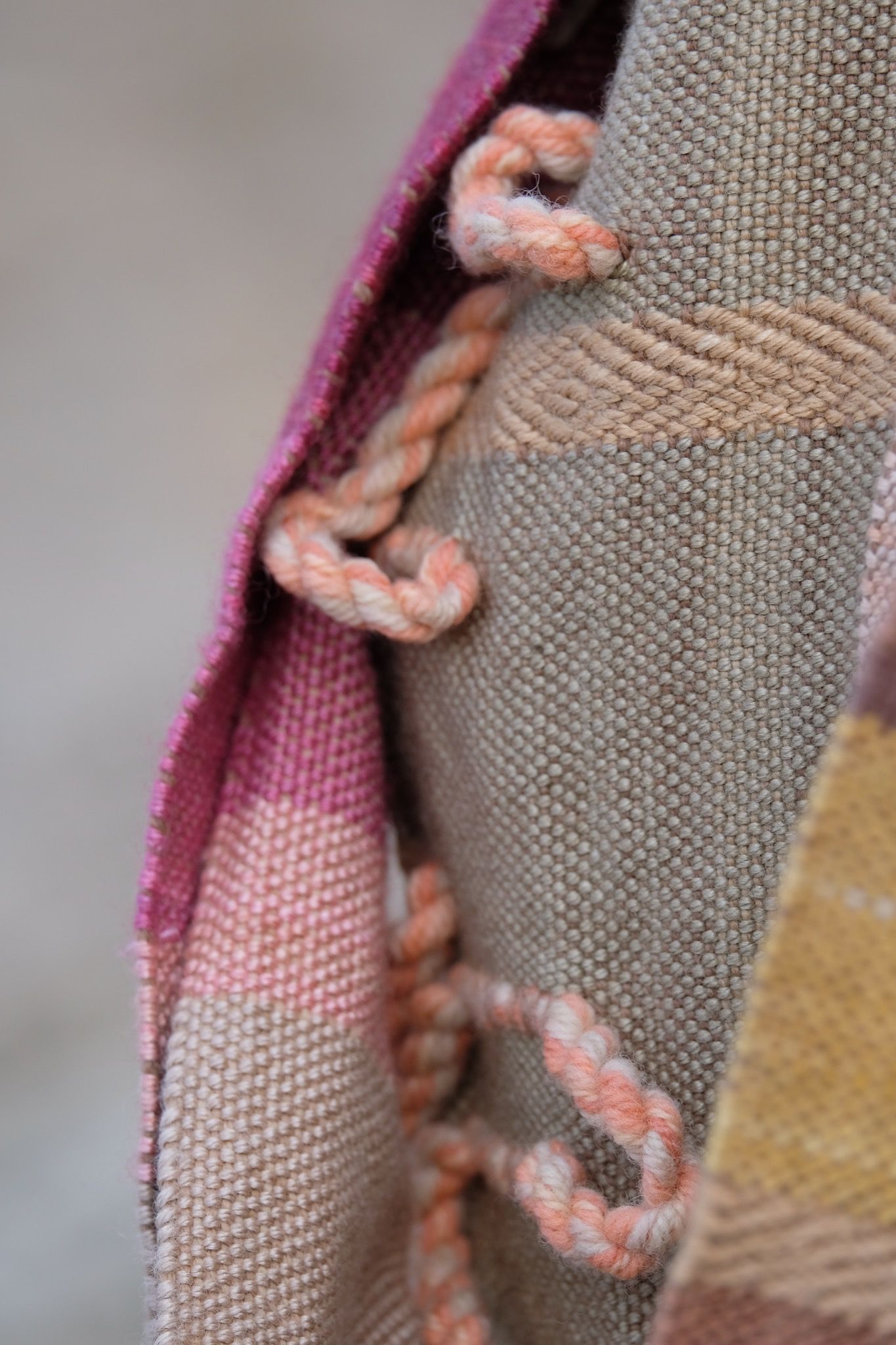 Detail of a naturally dyed brown, white, pink, salmon, yellow and green highly textured scarf on a white mannequin bust in the desert