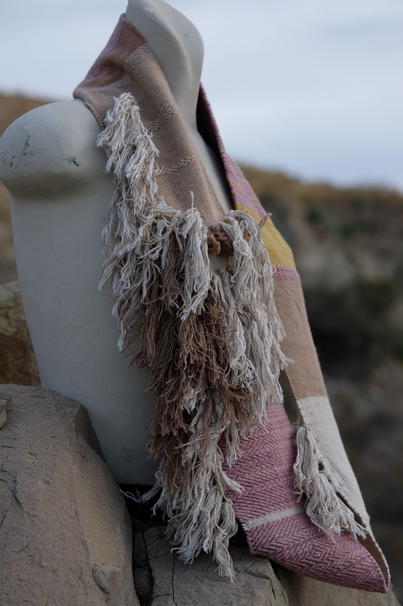 naturally dyed brown, tan white, mauve and gold infinity scarf on a white mannequin bust in the desert