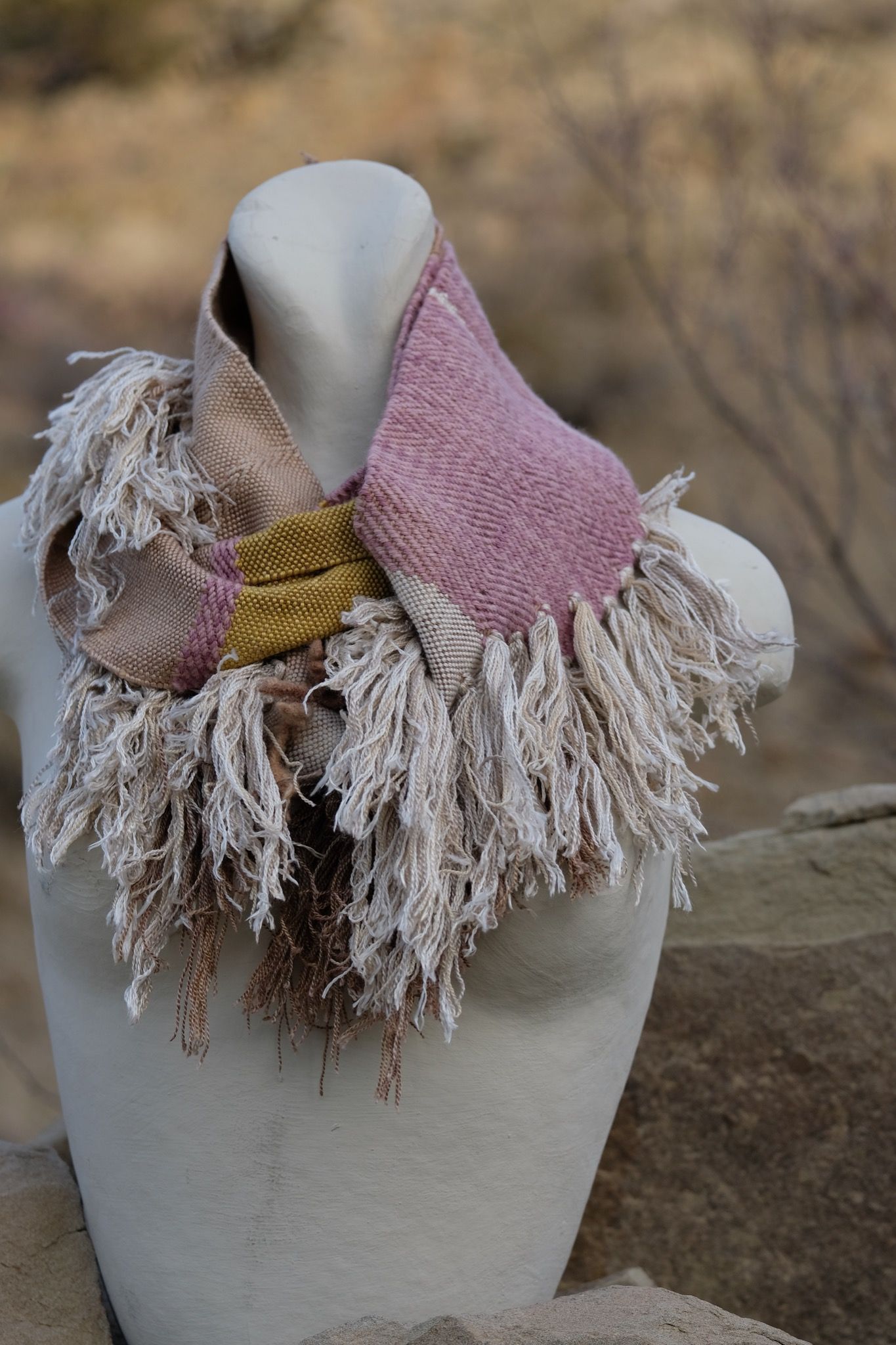 naturally dyed brown, tan white, mauve and gold infinity scarf on a white mannequin bust in the desert