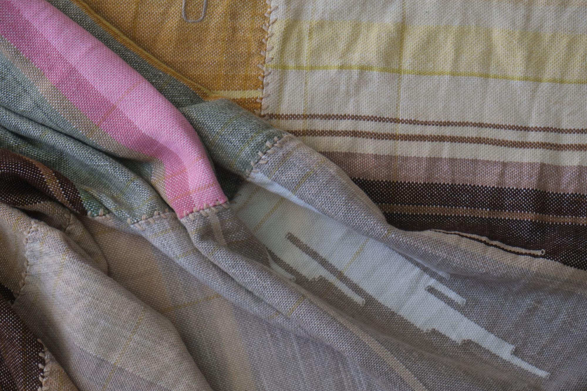 Detail of Handwoven Naturally Dyed Merino Ancient Dialogue Blanket laying on a wooden floor