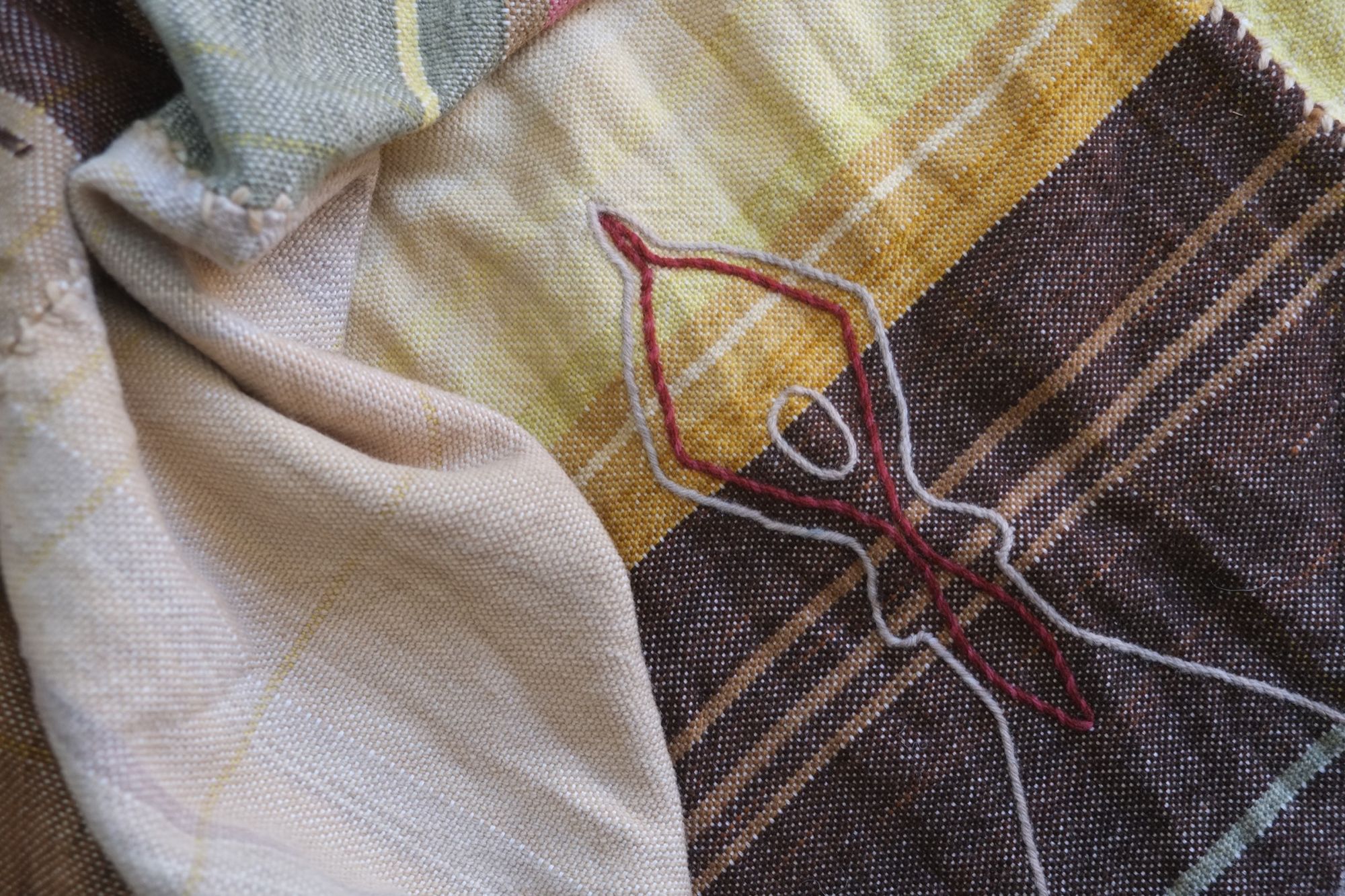 Detail of Handwoven Naturally Dyed Merino Ancient Dialogue Blanket laying on a wooden floor